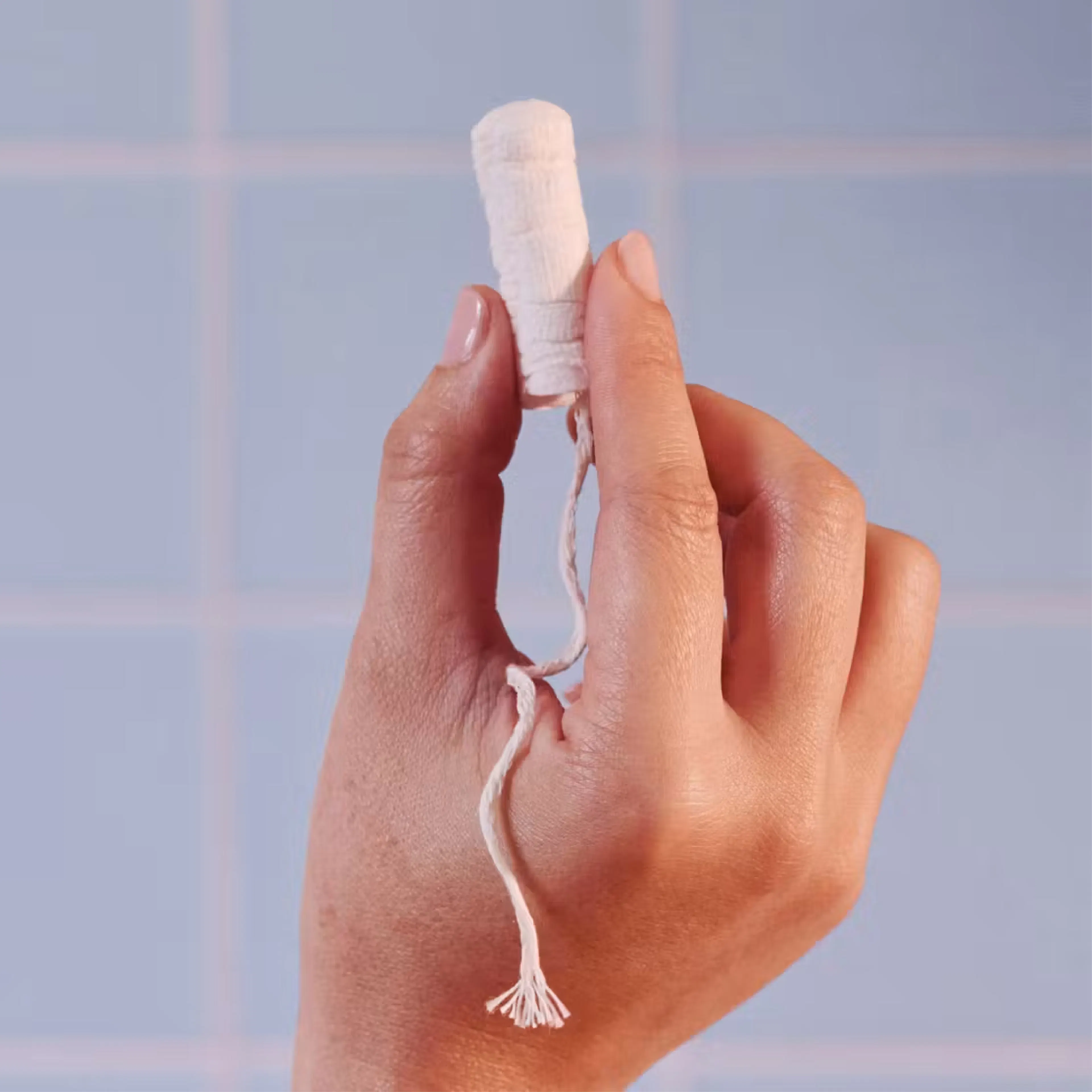 Hand holding up a white tampon