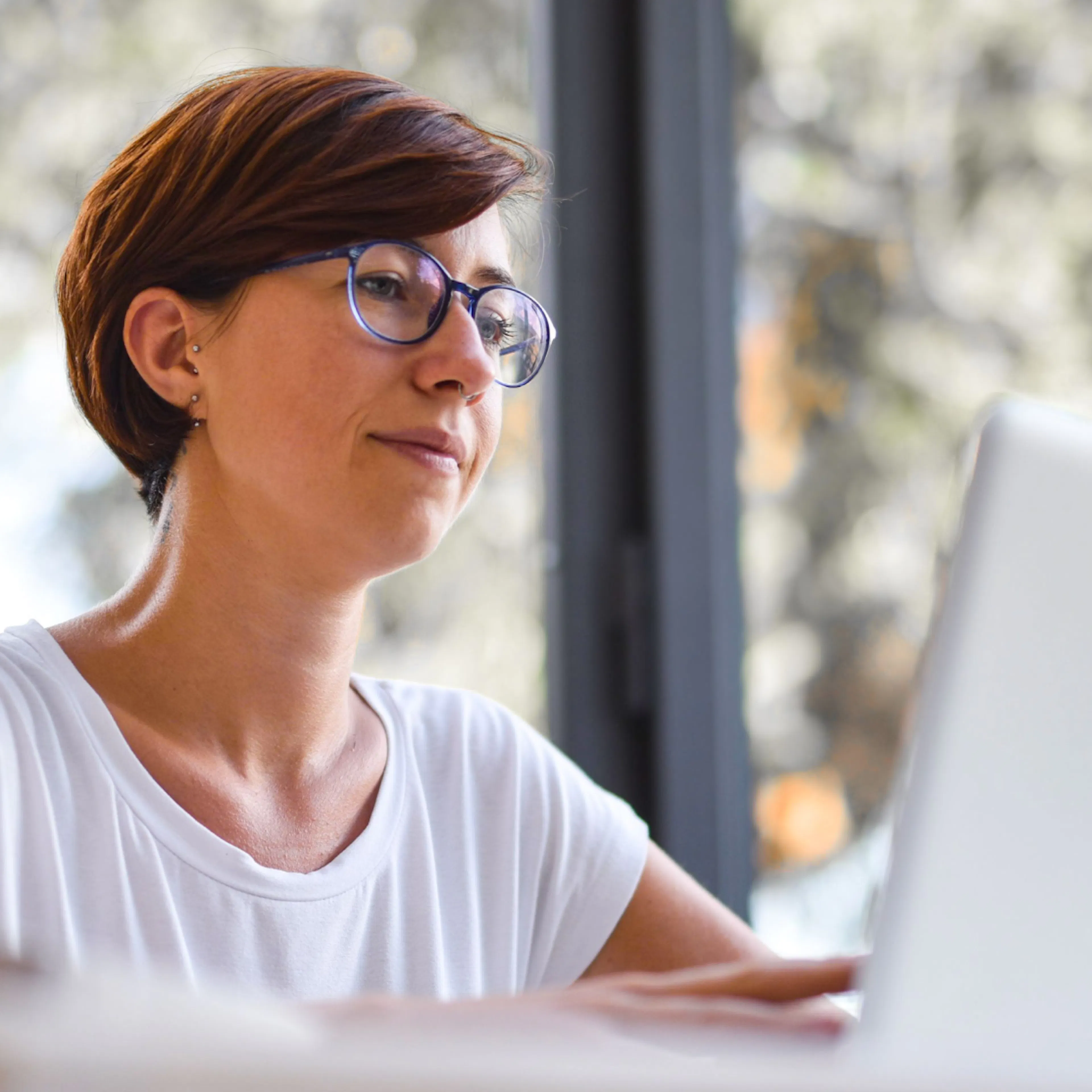 A woman in midlife with a neutral face, researching something on her laptop.