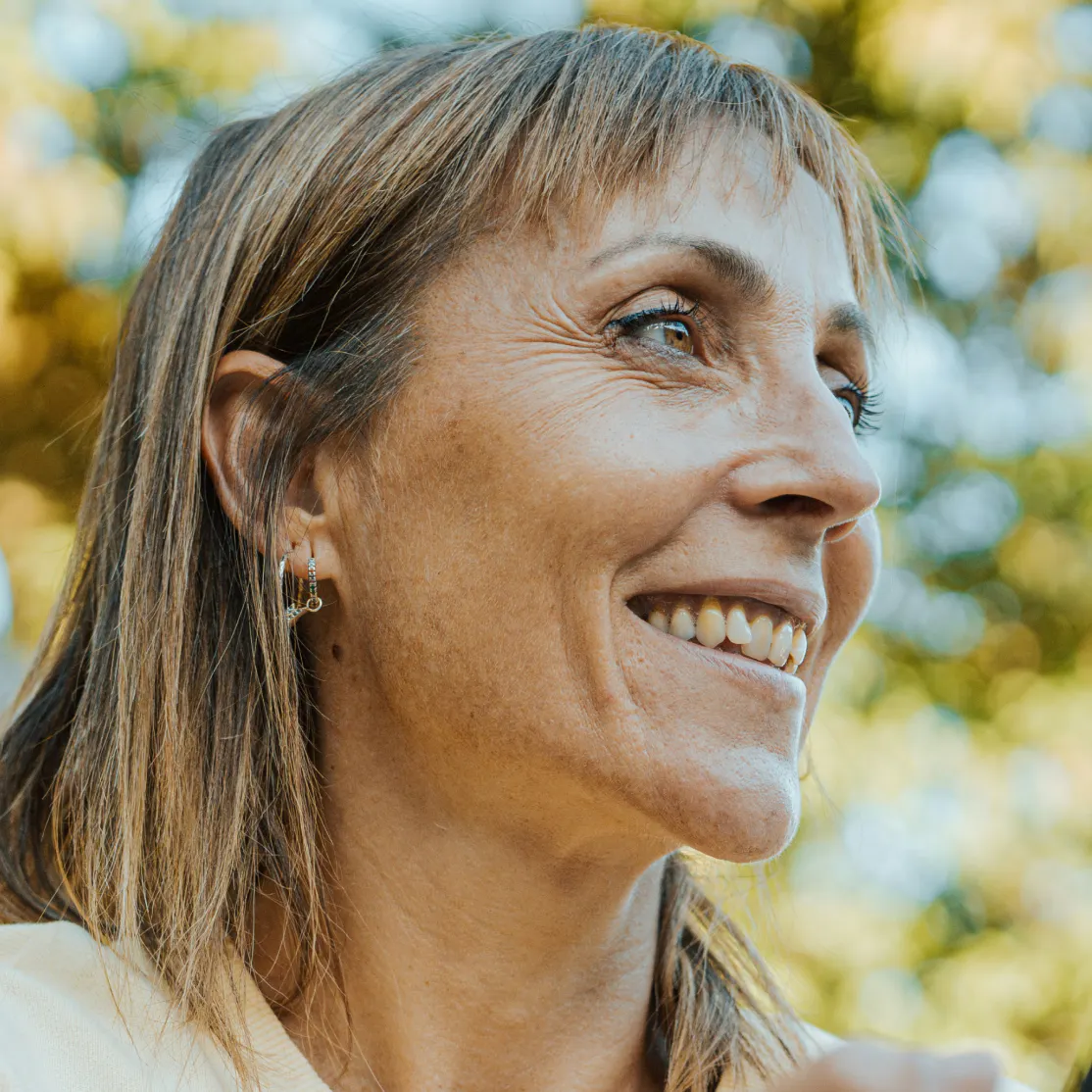 A close-up photo of a Denver woman in menopause looking to the side while she stands outside.