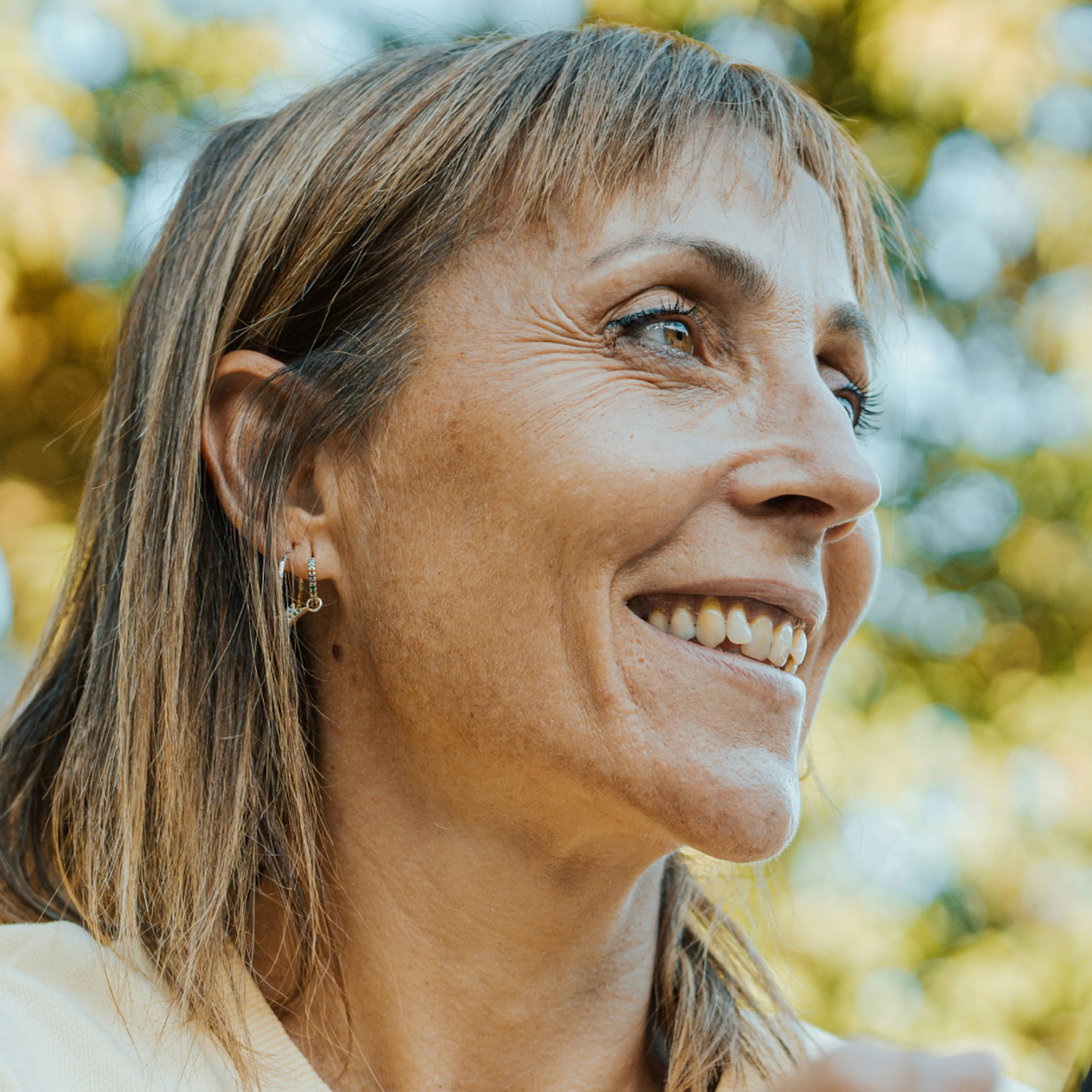 A close-up photo of a Denver woman in menopause looking to the side while she stands outside.