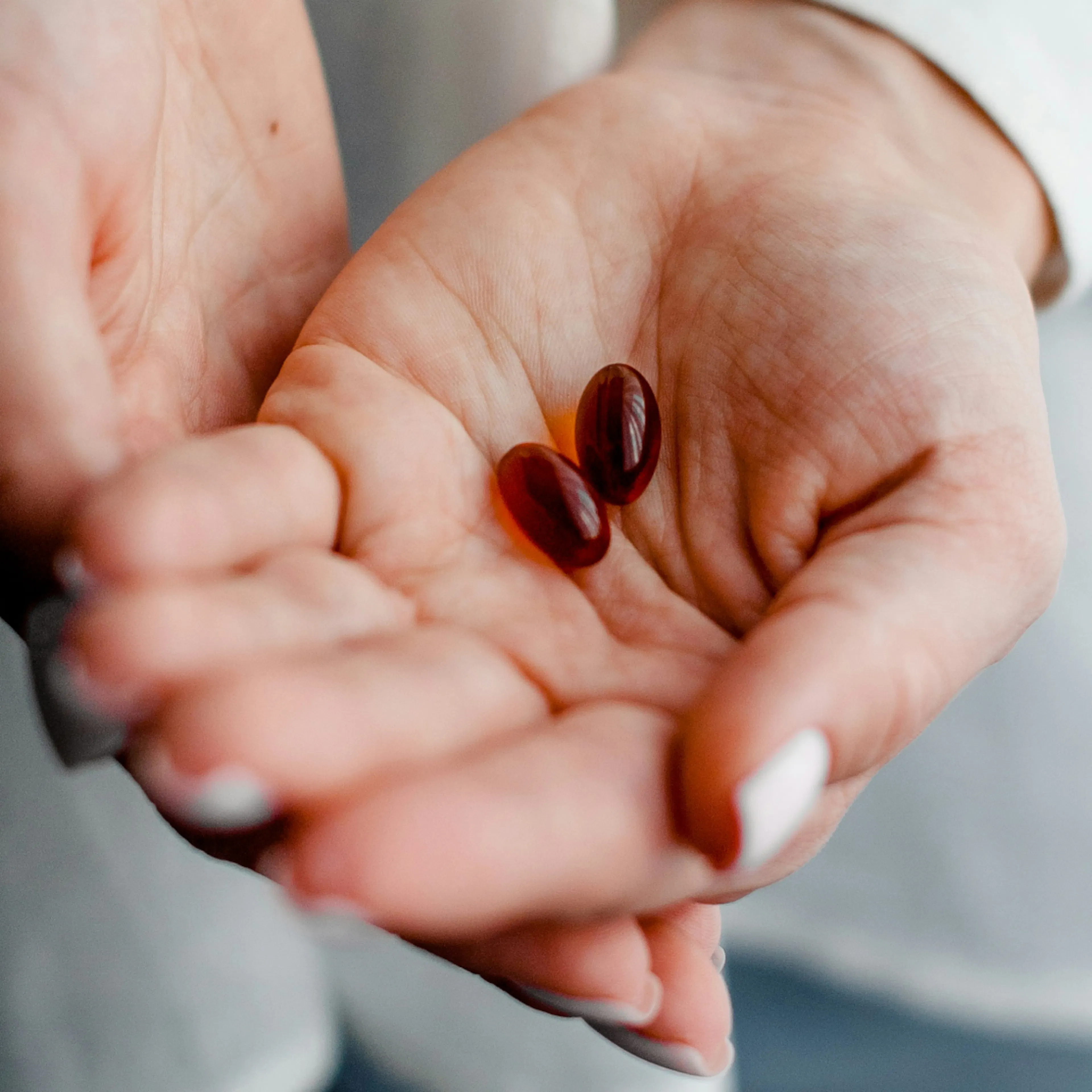 A close-up photo of a woman holding two capsules in her hand.