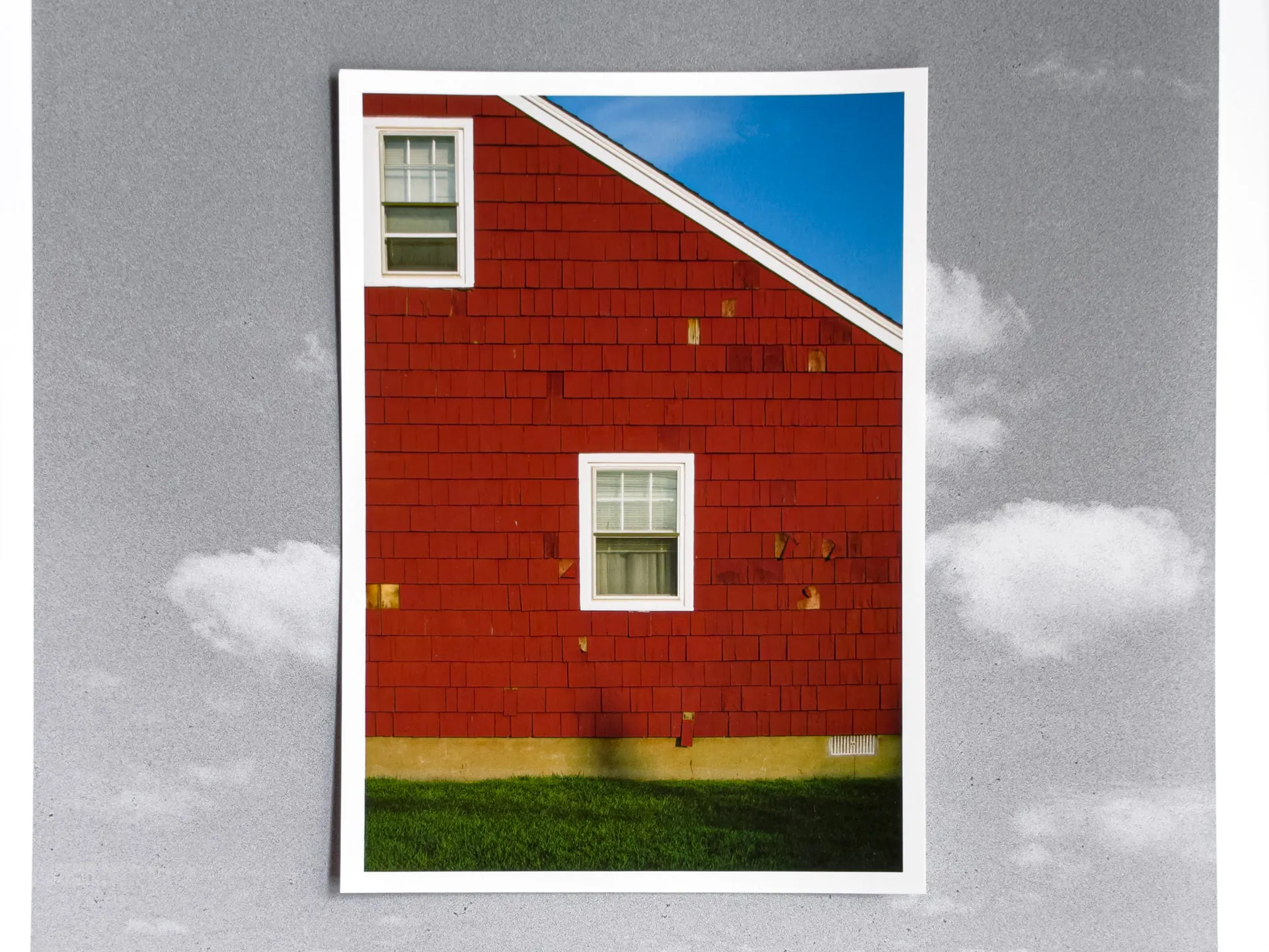 Print of a red shingled house shot on Ektachrome 100 film, laid on a larger black and white film print of clouds, both printed on Polar Matte paper