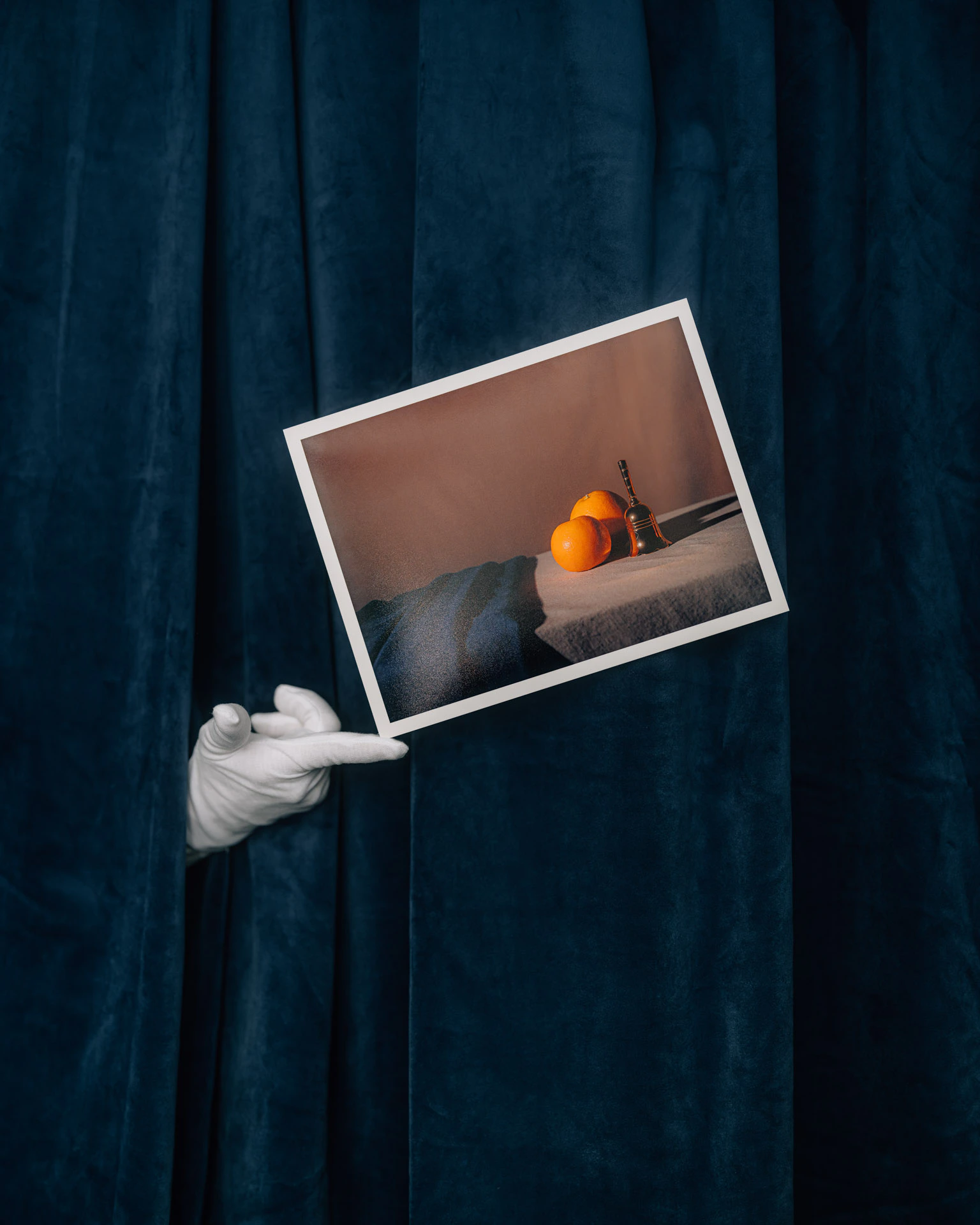 The Shape of Thought from Saint Citrus printed on Red River Paper, held by a white-gloved hand reaching through blue velvet curtains