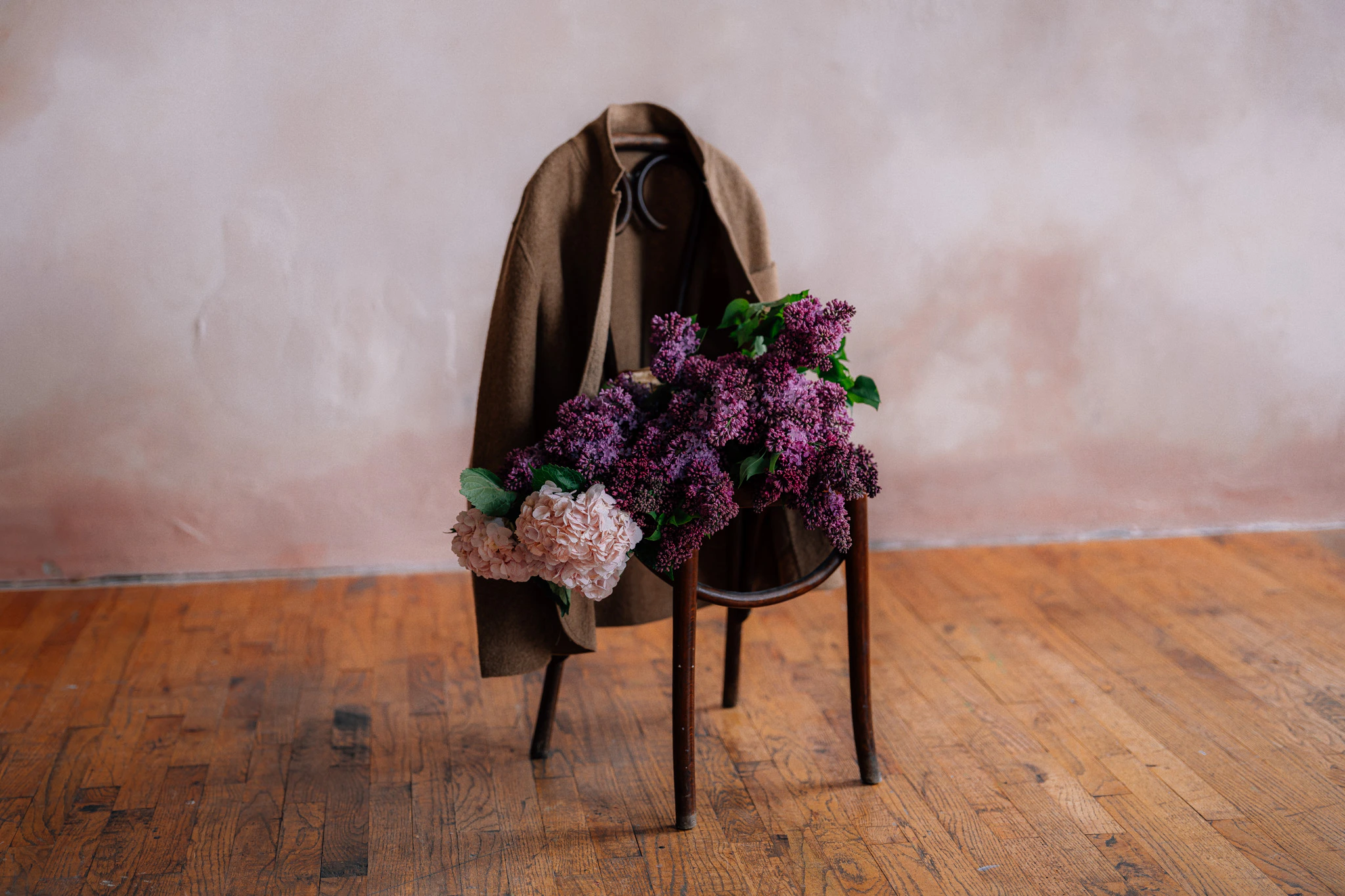 pink and purple lilacs and hydrangeas flower bouquet on chair with felted jacket