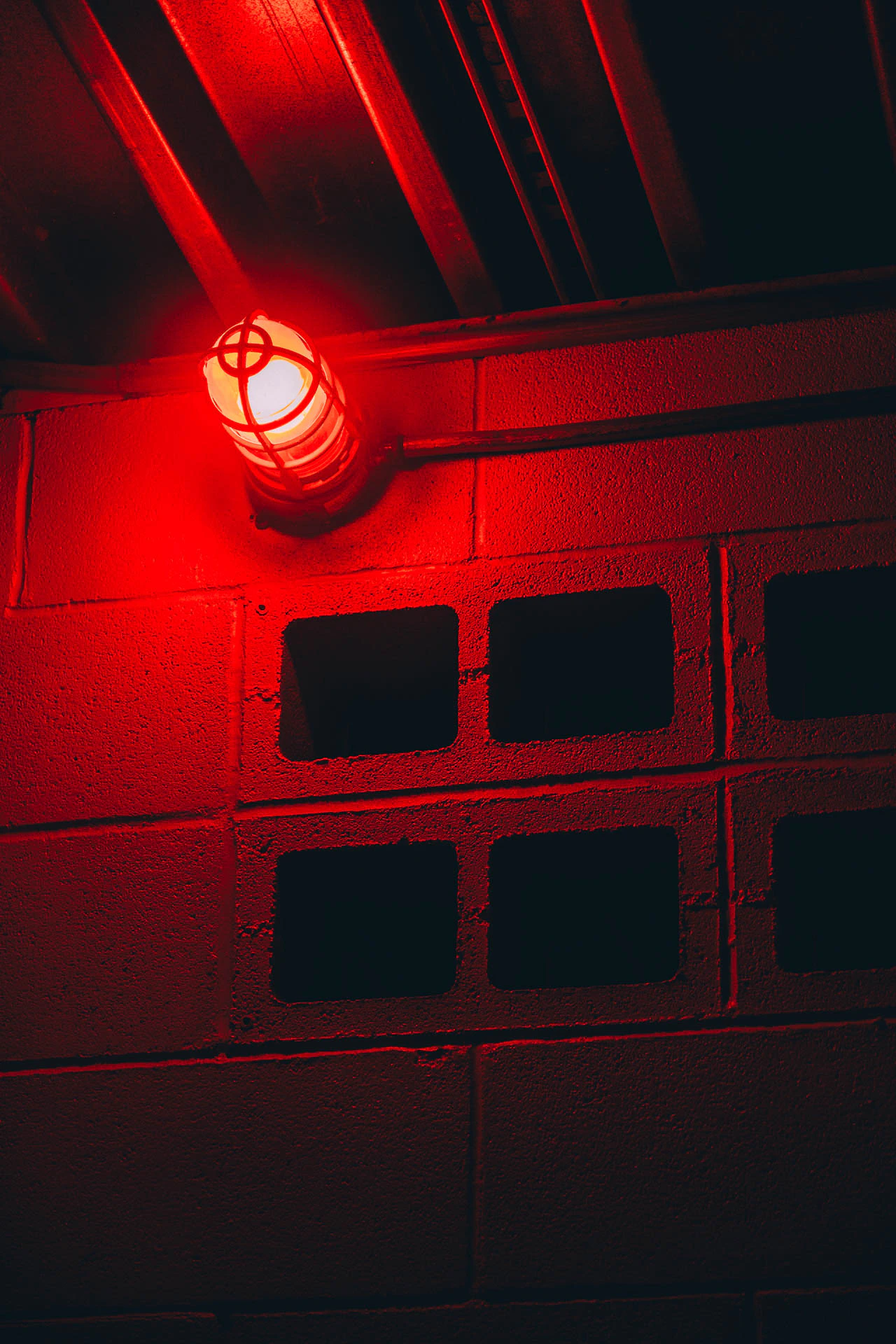 A red light lighting up breeze blocks in a bathroom at night. Red Bathroom #02 from Jonathan Grado's Hold Down to Flush.