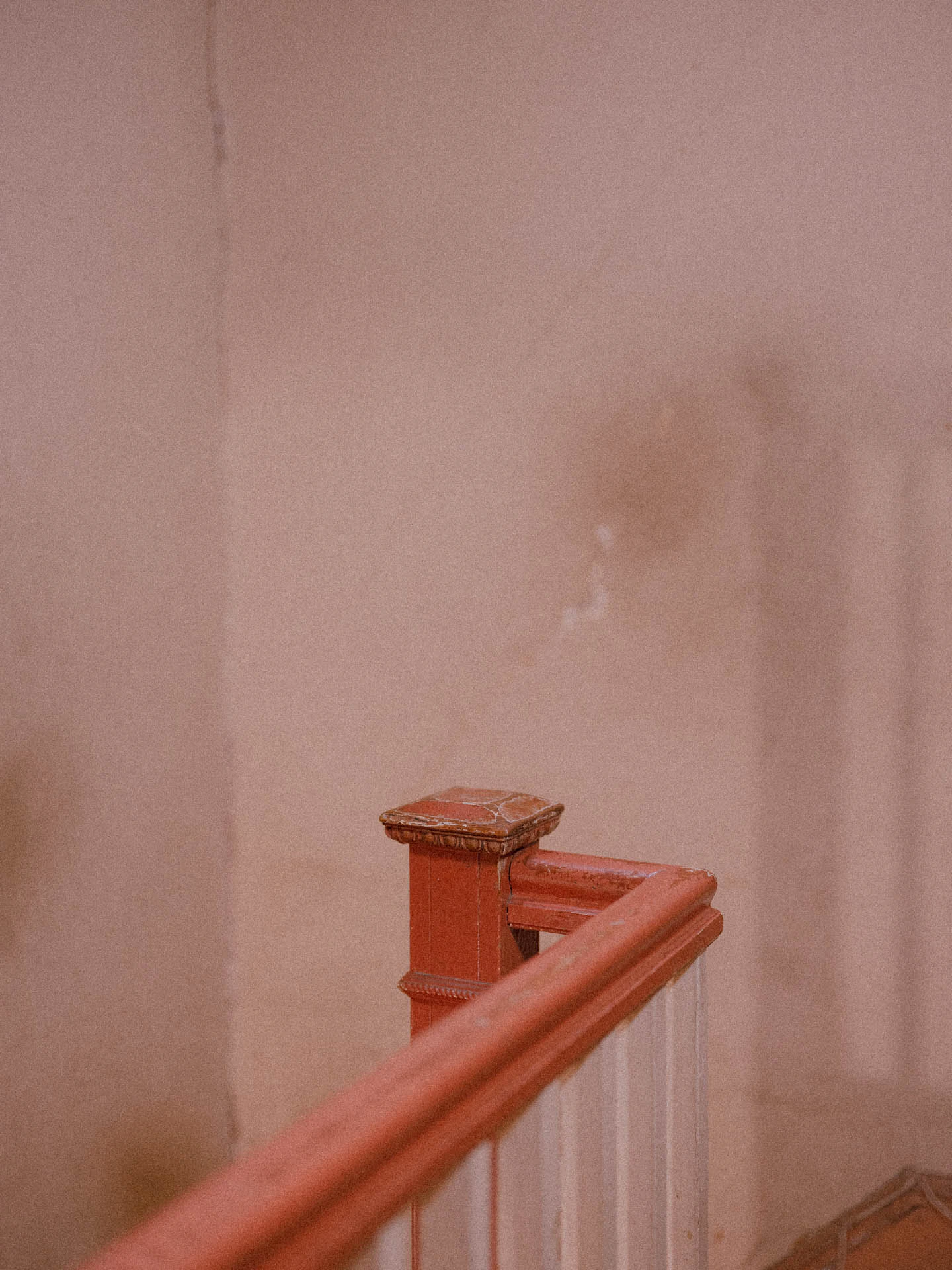 an orange banister curving in an old stairwell