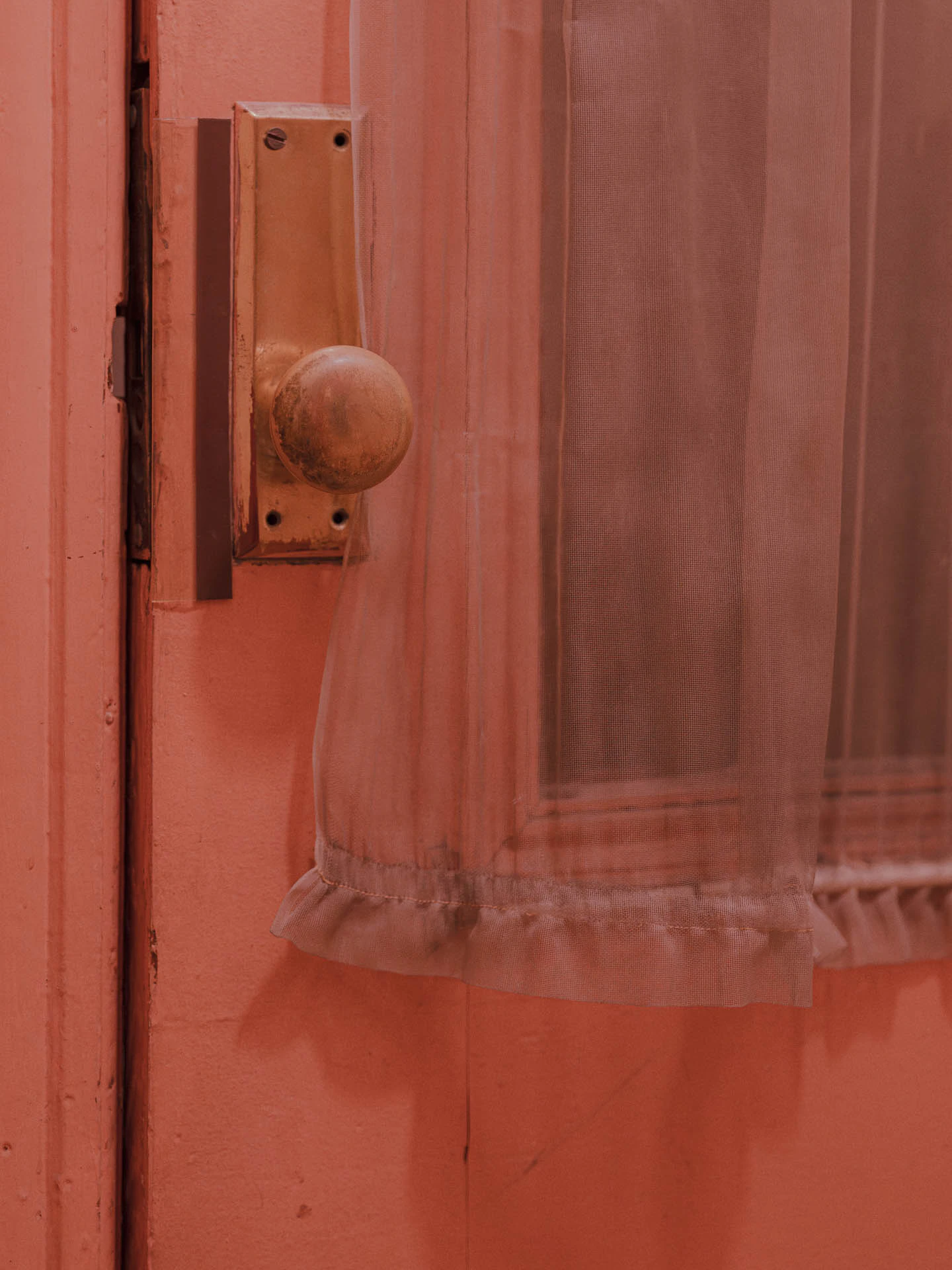 pink door and knob on a dreamy and grainy old door with a window curtain