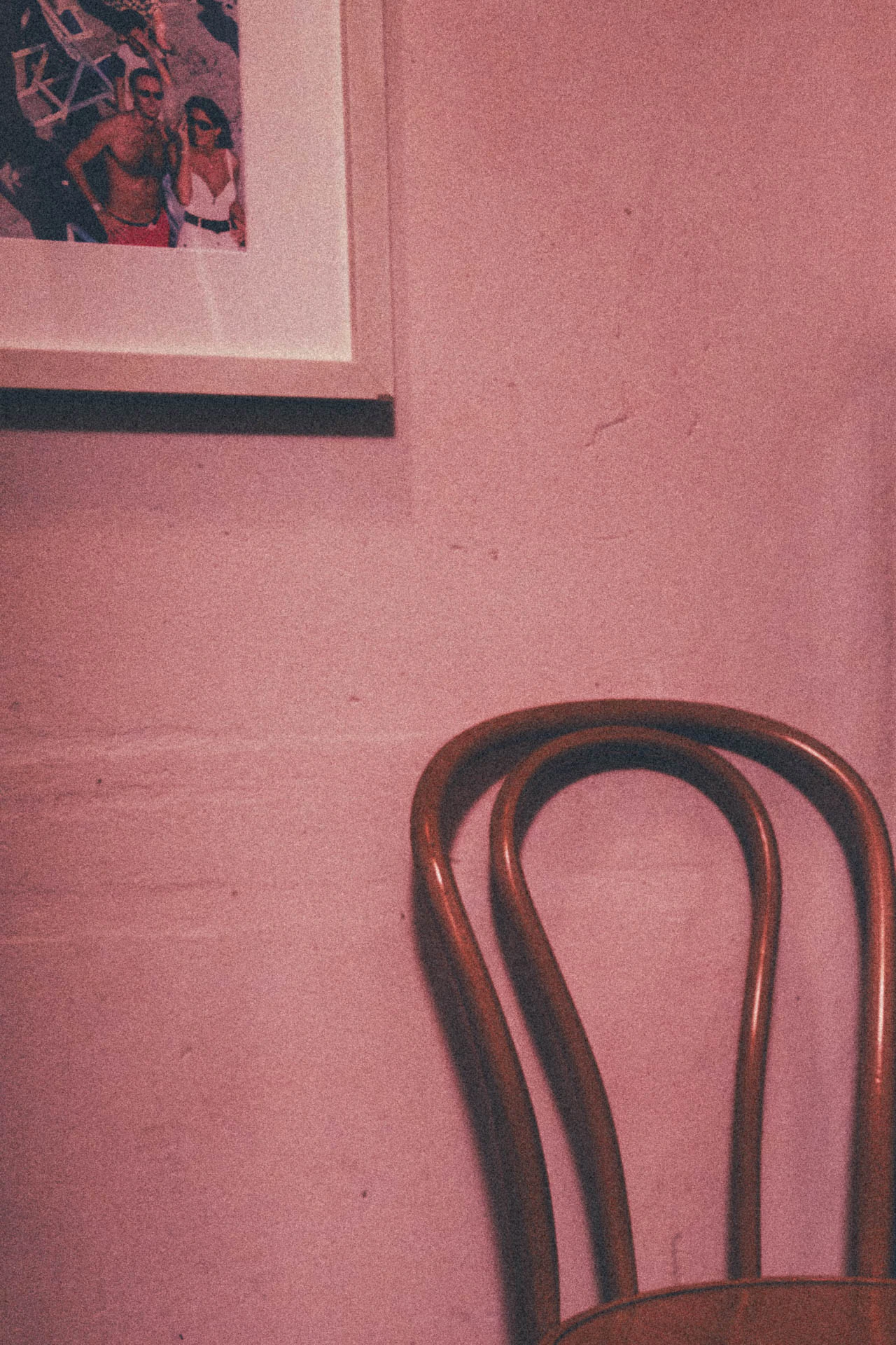 A chair in a pink room under a photo of a couple on vacation. Look Honey, a Chair from Jonathan Grado's Dirty Static.