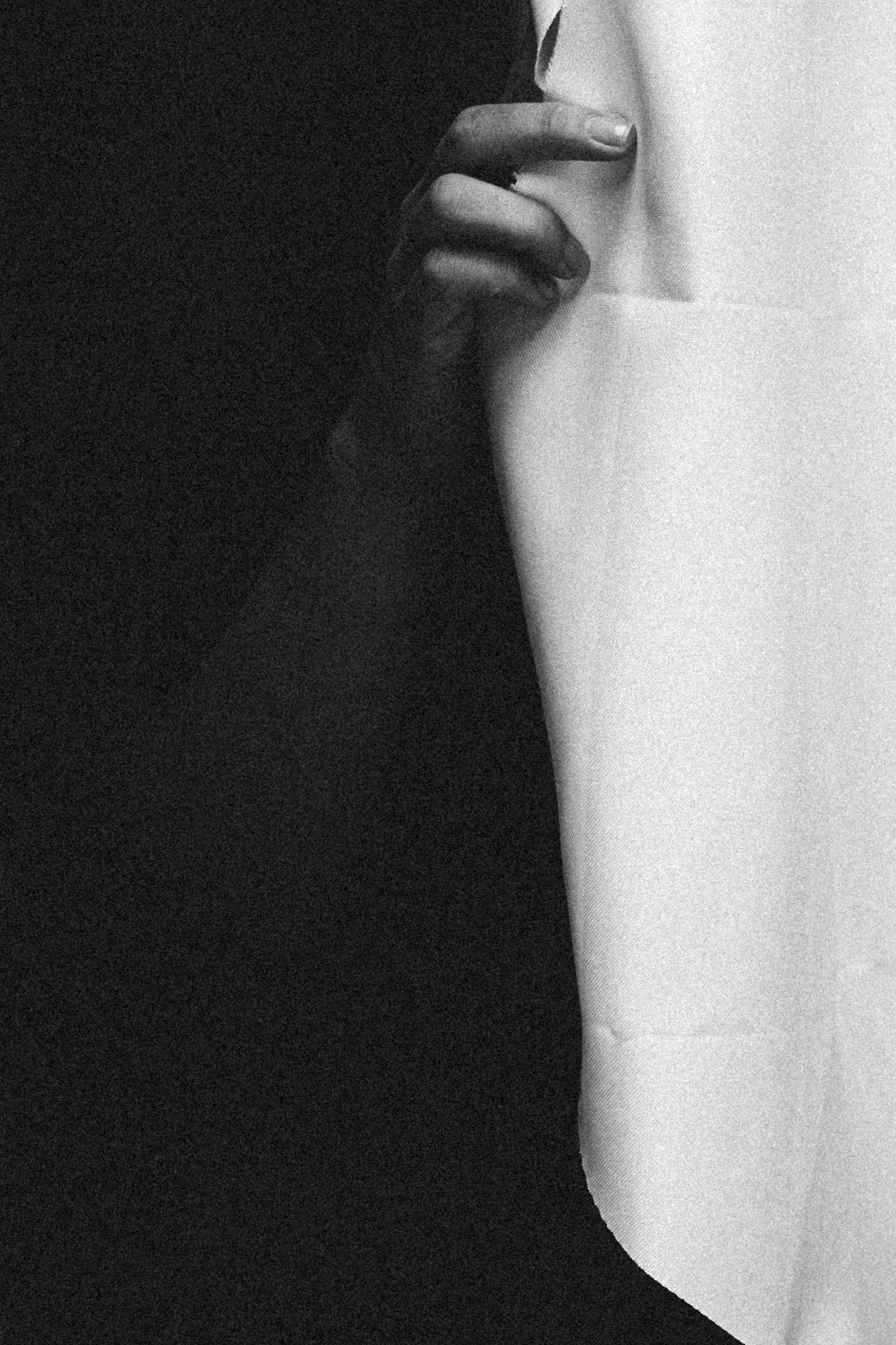 Hand holding open a window curtain in black and white. Hide and Seek from Jonathan Grado's Dirty Static.
