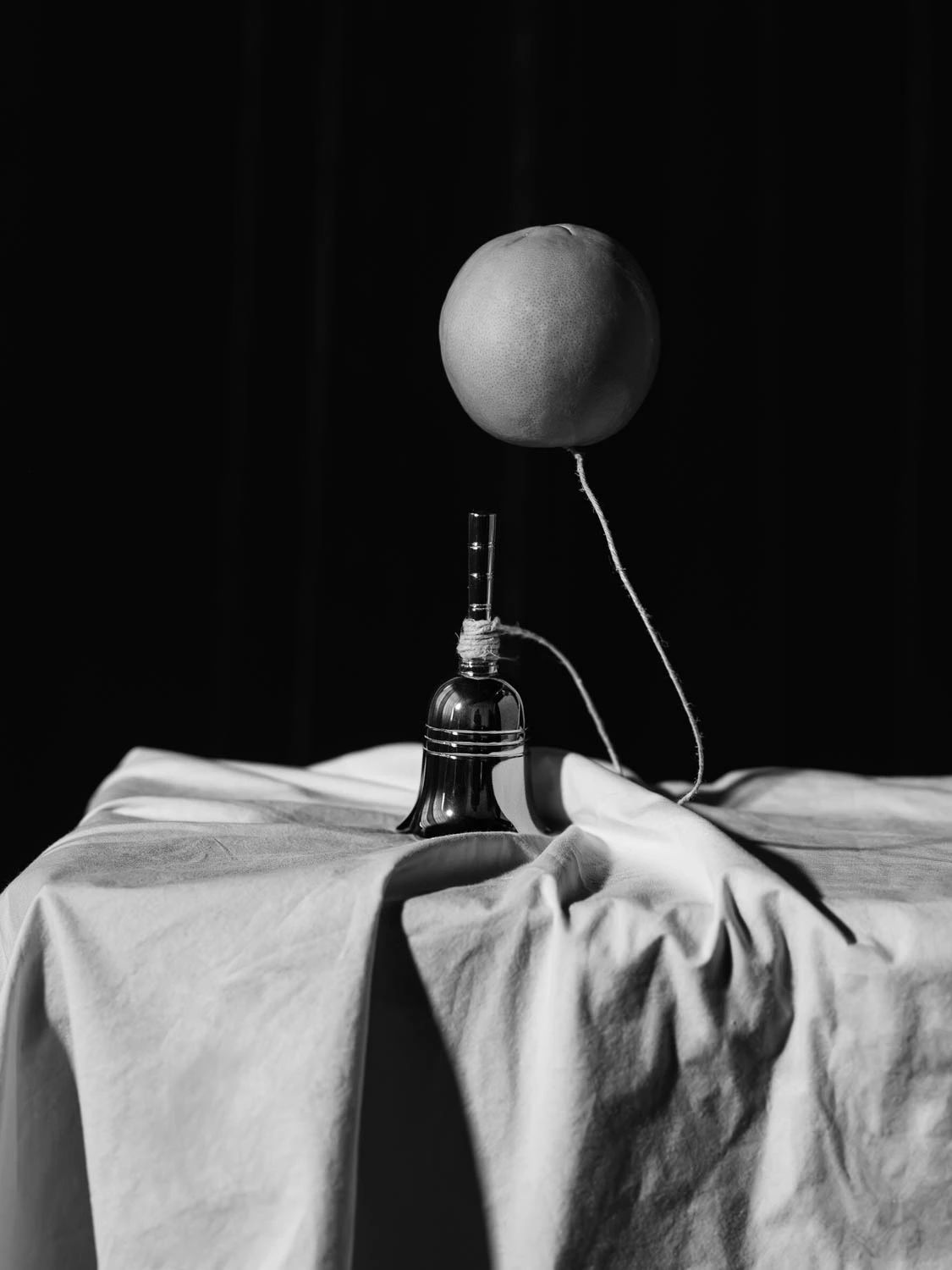 An orange floating above a handbell for saint citrus