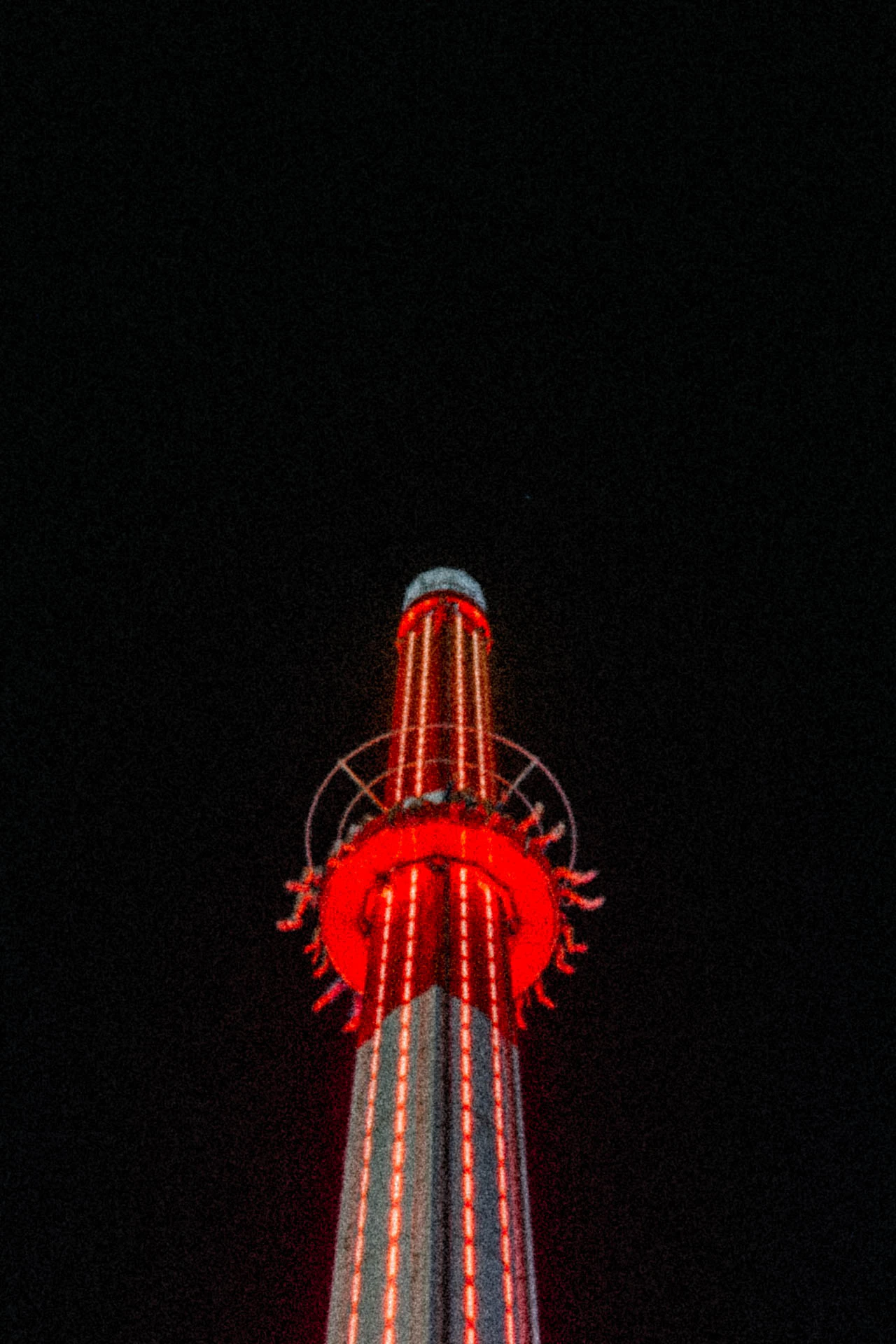 The red and white lighthouse drop zone fantasy island ride at night