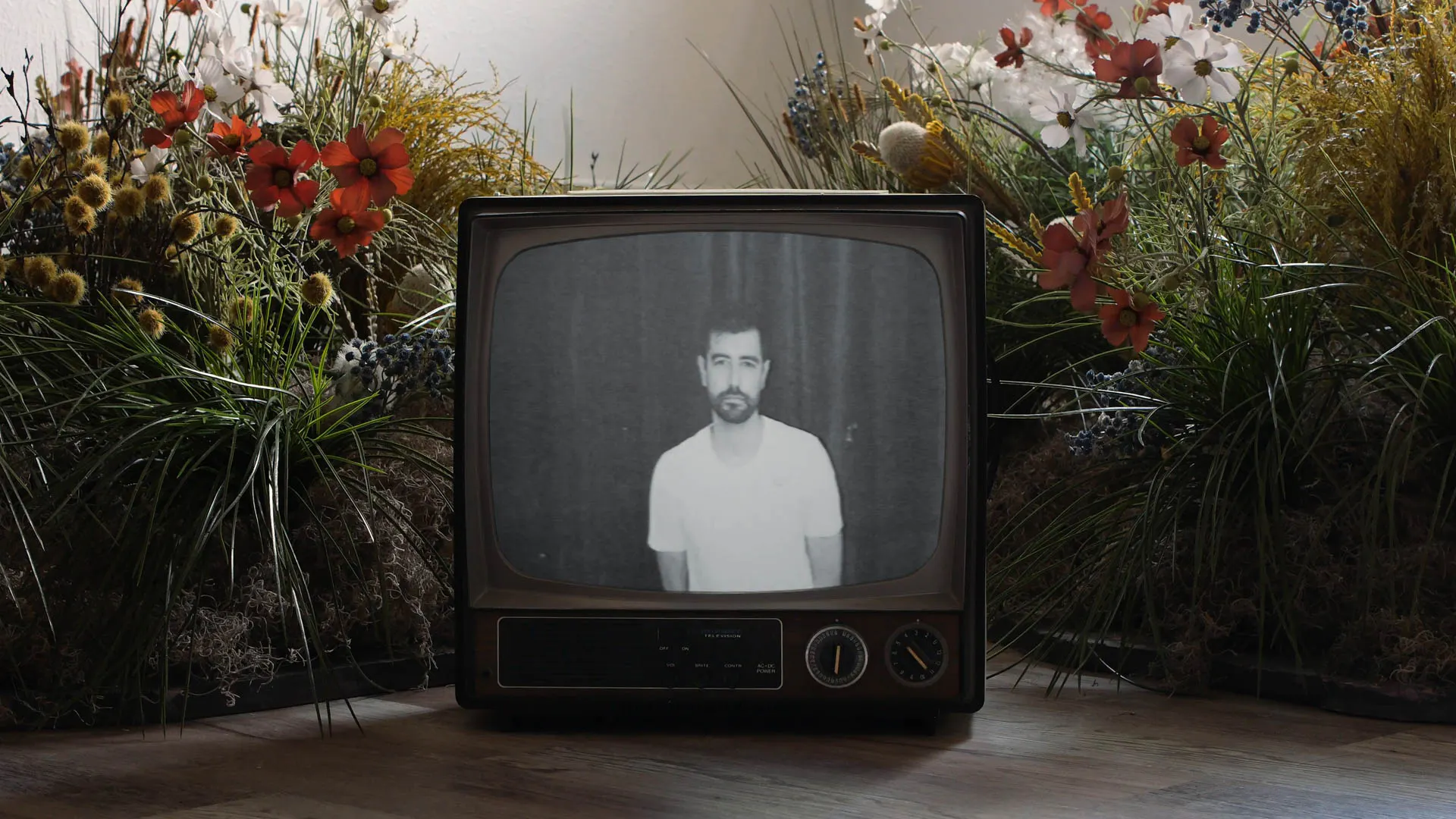 An old CRT tv in a garden with Jonathan Grado on screen in front of blue velvet. For Overthinking video