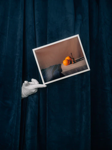 white glove holding printed photo on red river paper in front of blue velvet