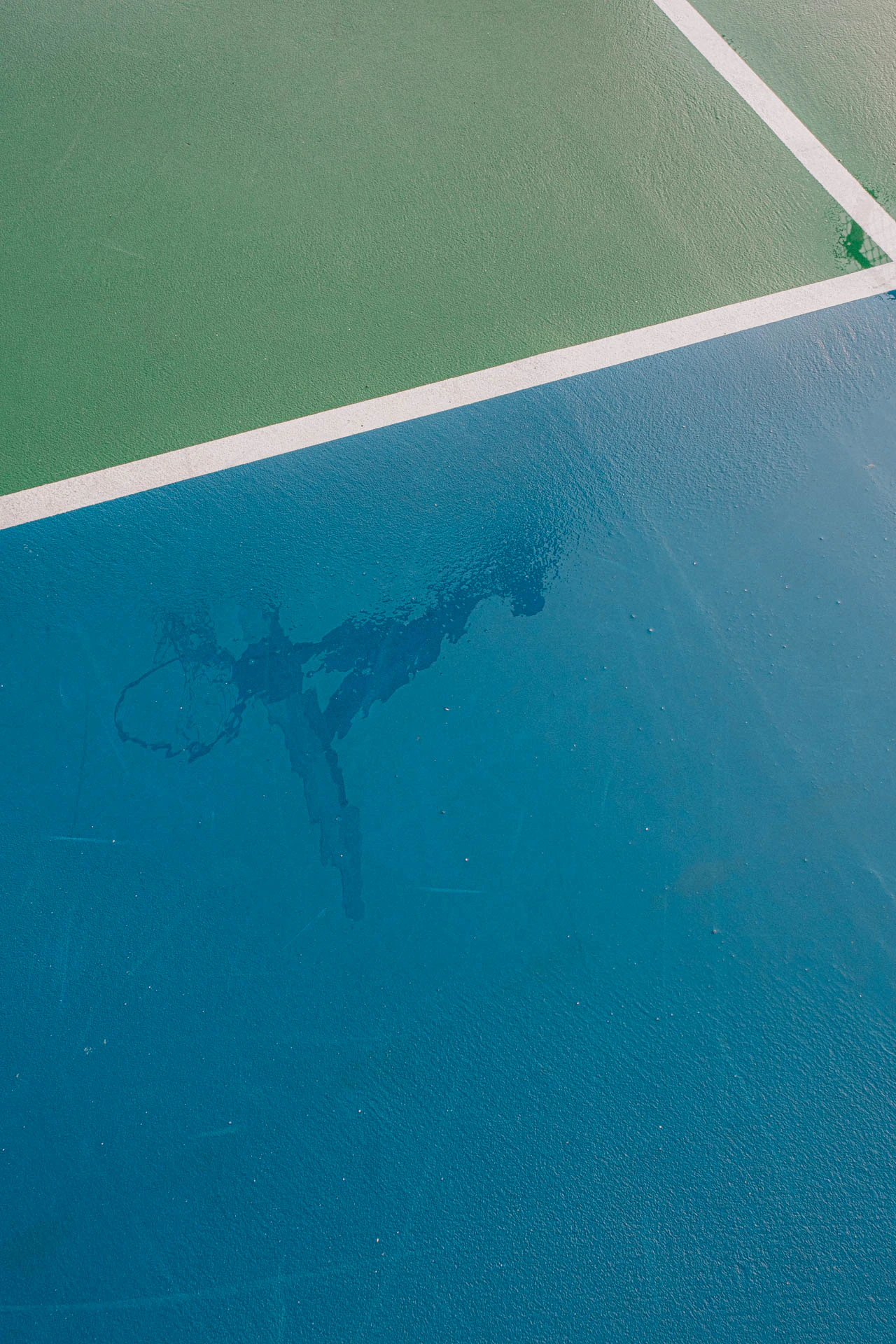 basketball hoop in the reflection of a rainy blue and green court