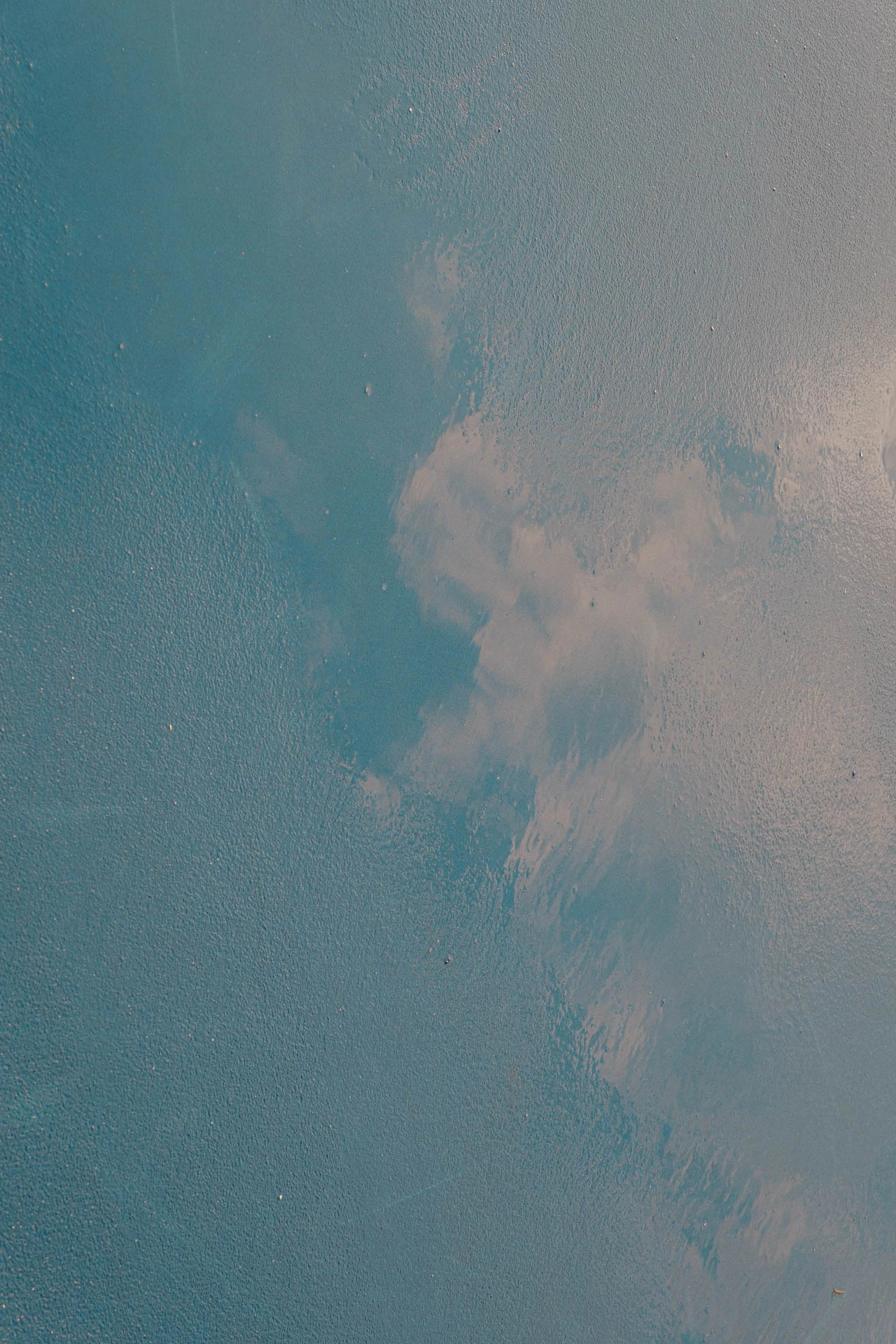 clouds in the sky in the reflection of a rainy blue and green basketball court
