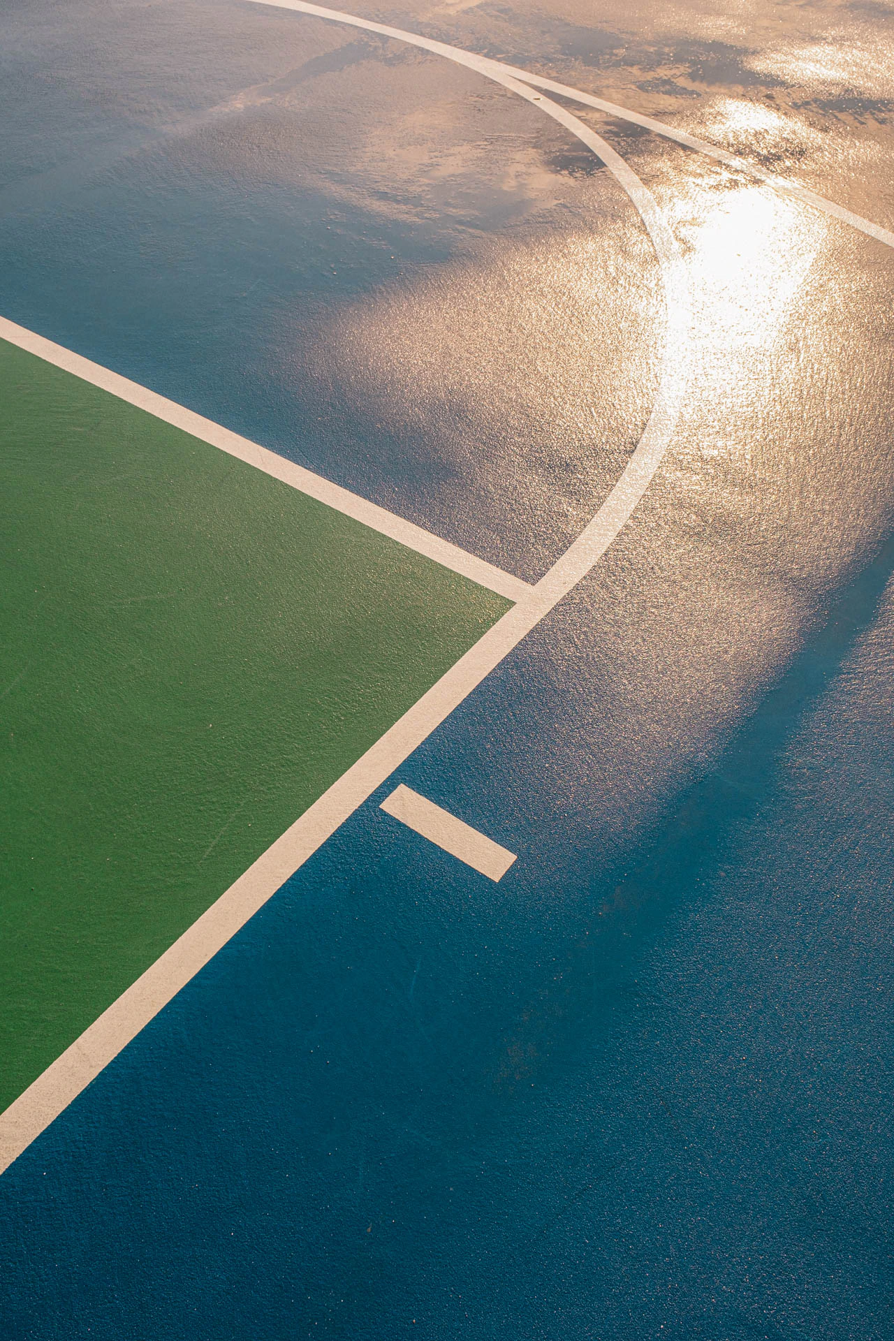 clouds in the sky in the reflection of a rainy blue and green basketball court