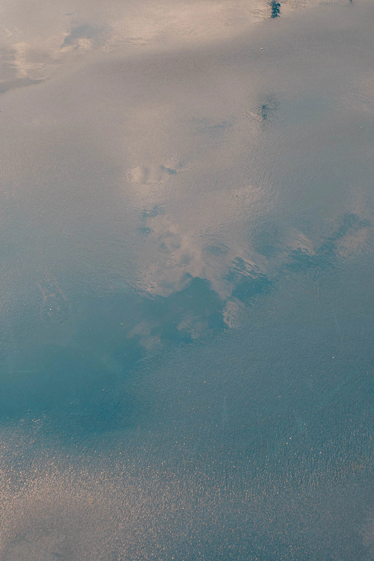 clouds in the sky in the reflection of a rainy blue and green basketball court