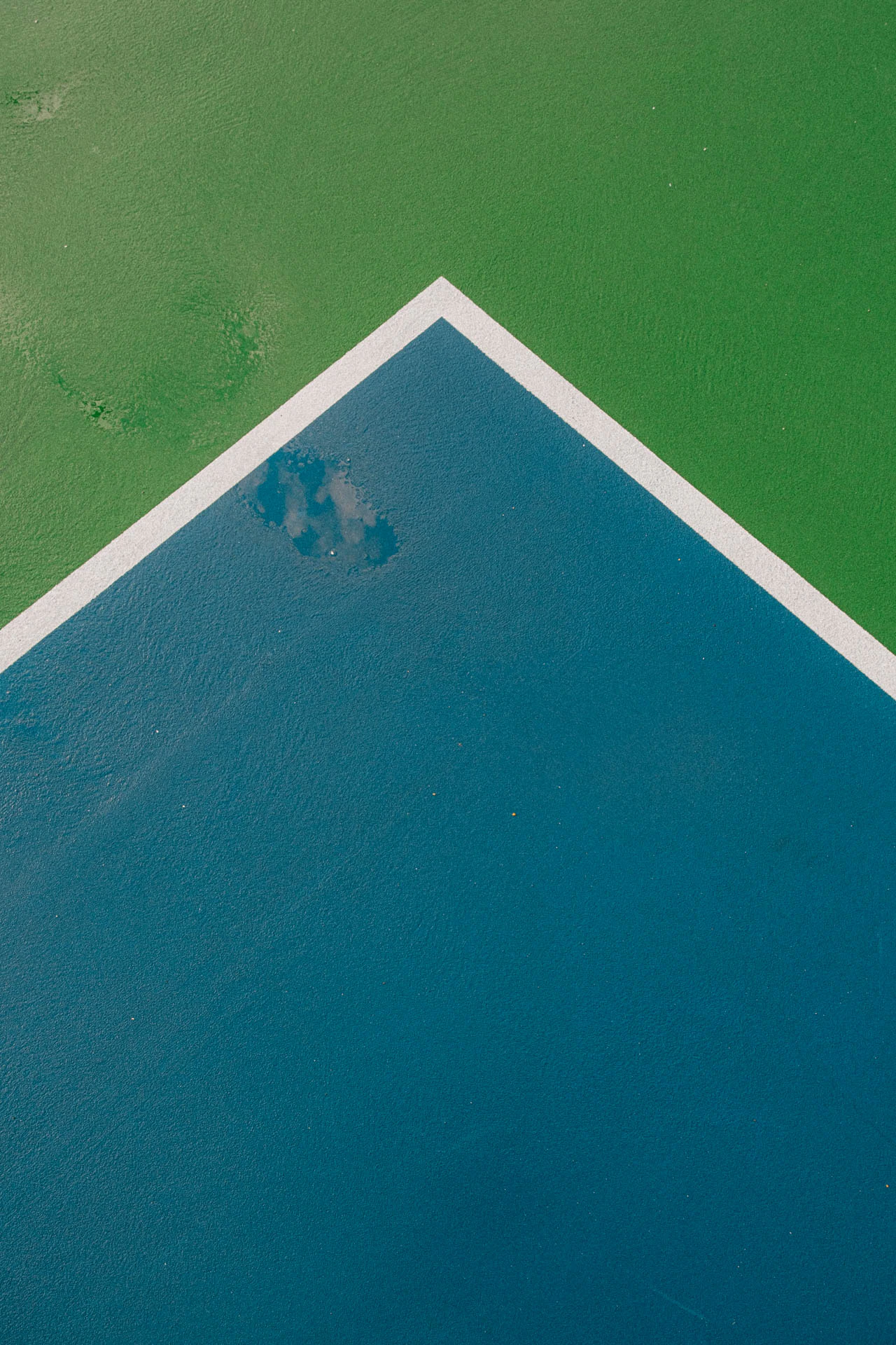 paint lines on a blue and green basketball court after a storm