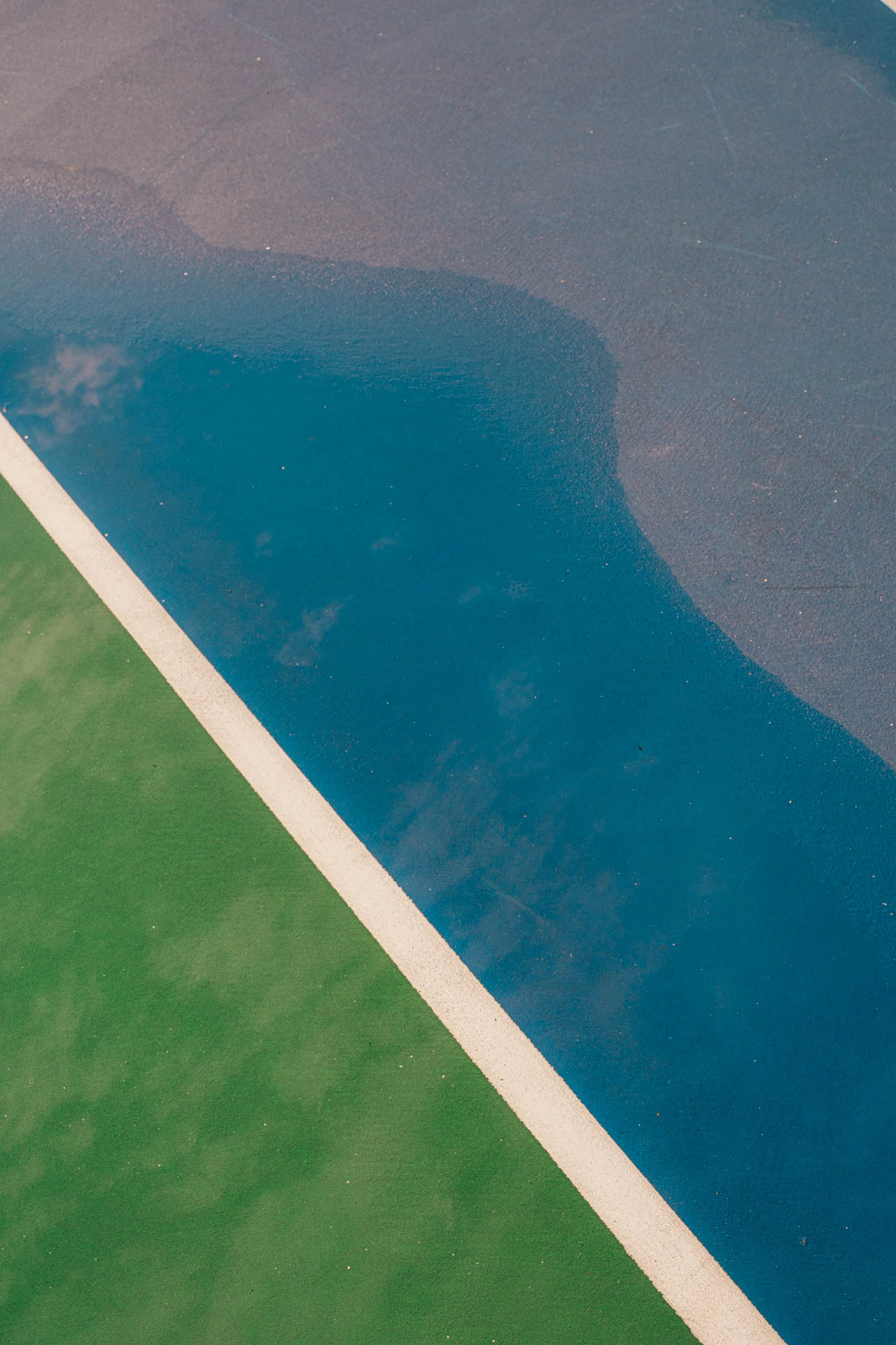 paint lines on a blue and green basketball court after a storm