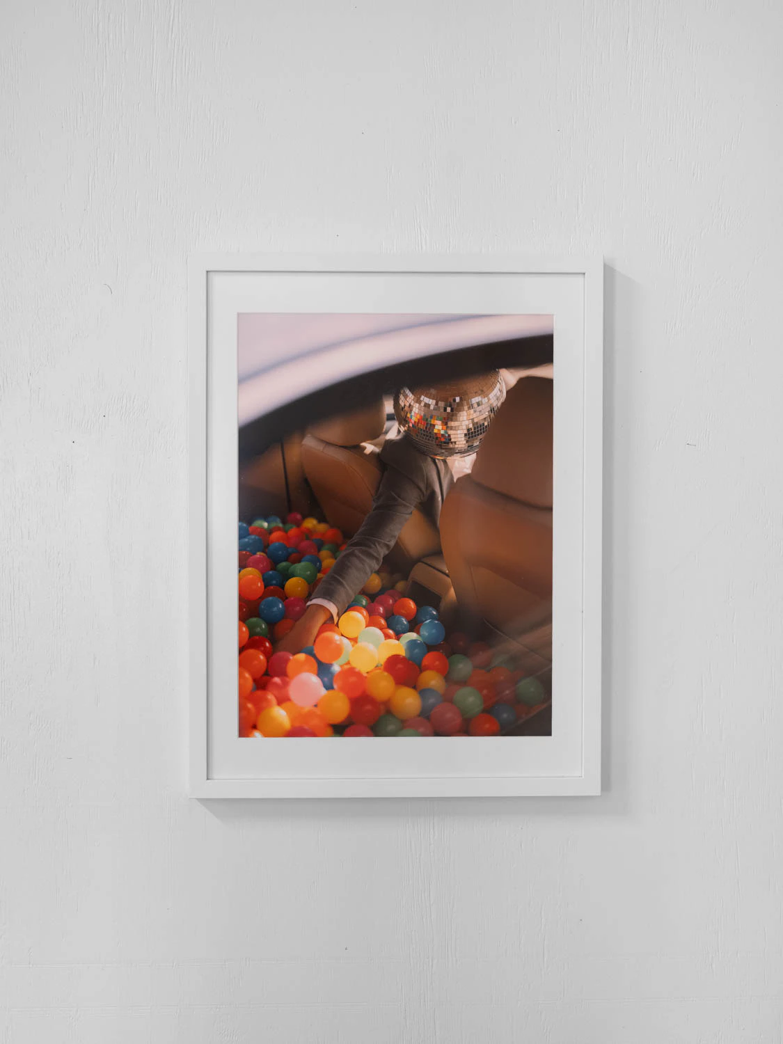 framed photo from happy hour series at sxsw 2025. Man with disco ball head reaching in to a ball pit in their car