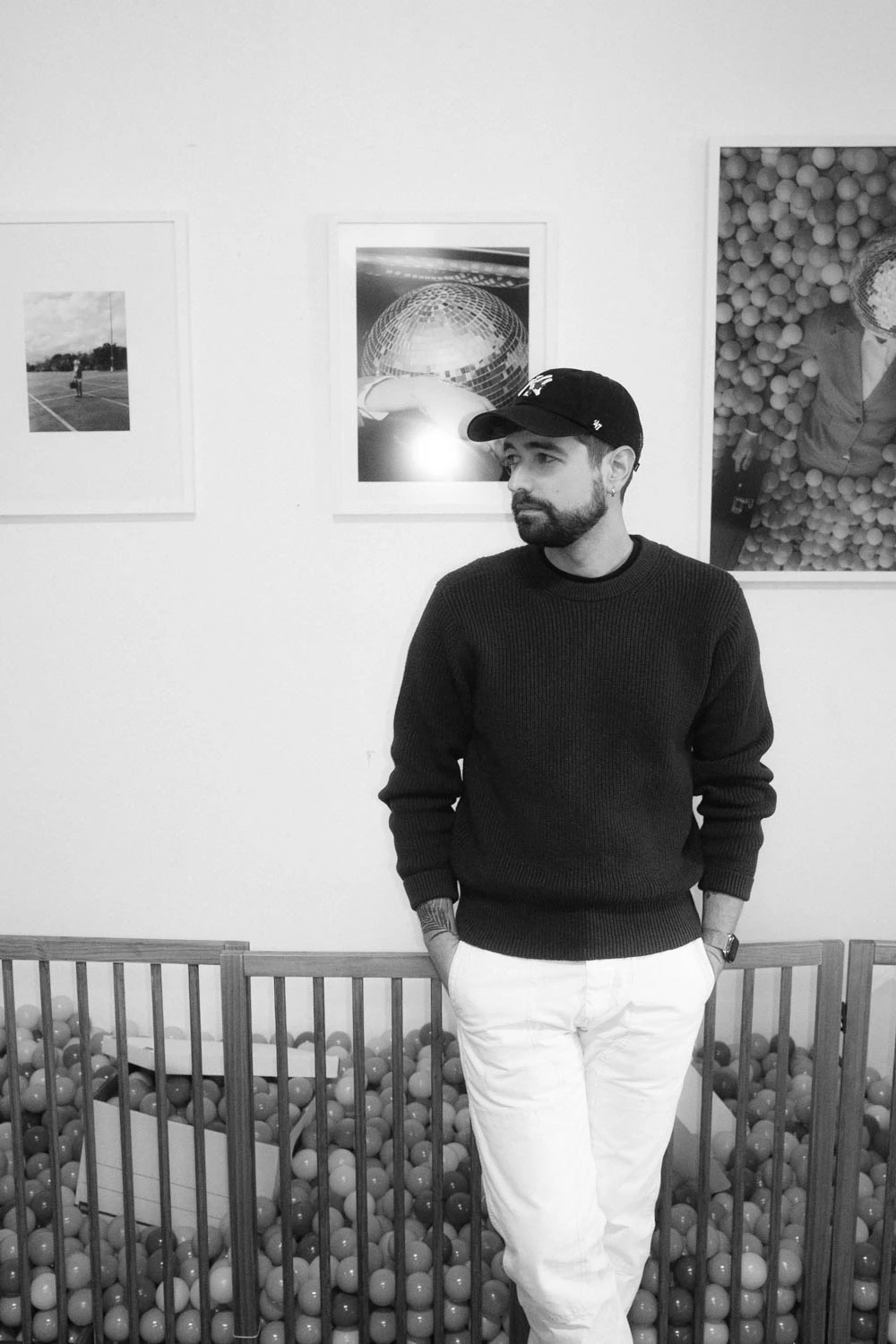 Jonathan Grado wearing a hat in front of framed happy hour series installation at sxsw in black and white at SXSW 2025