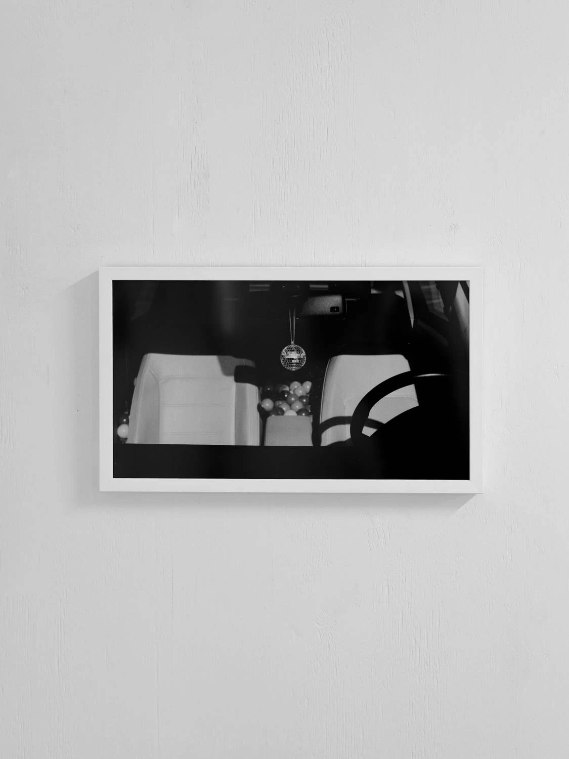 framed photo from happy hour series installation of a disco ball hanging on a rearview mirror in a car, for sxsw 2025. black and white.