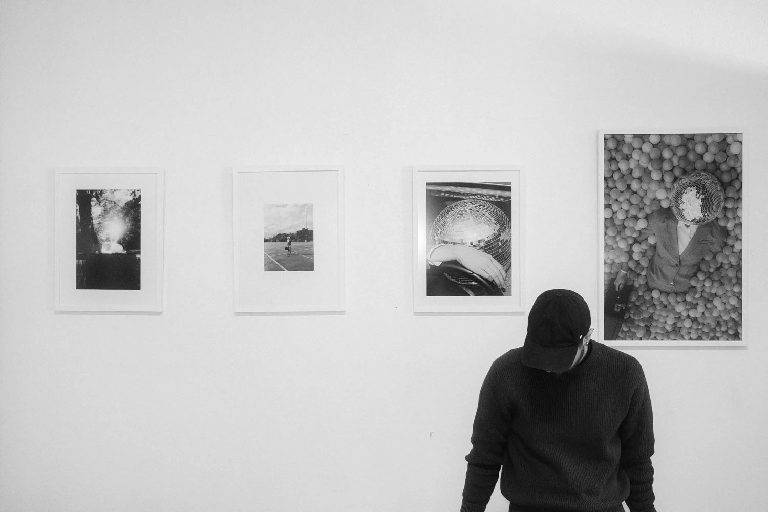 Jonathan Grado with head down in front of framed happy hour series installation photos at sxsw in black and white at SXSW 2025
