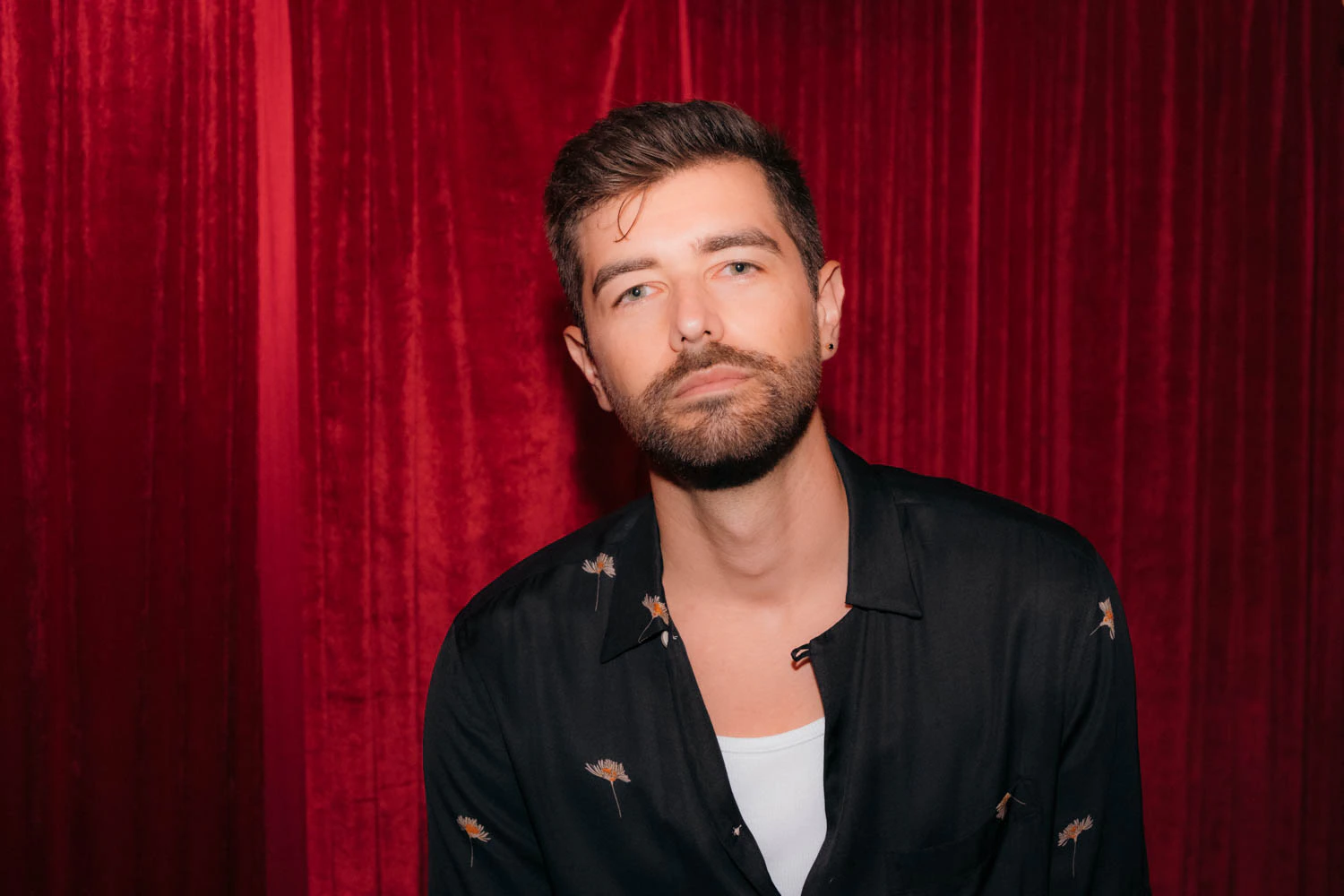Portrait of Jonathan Grado in a daffodil shirt using heightened look flash photography. Red velvet background.