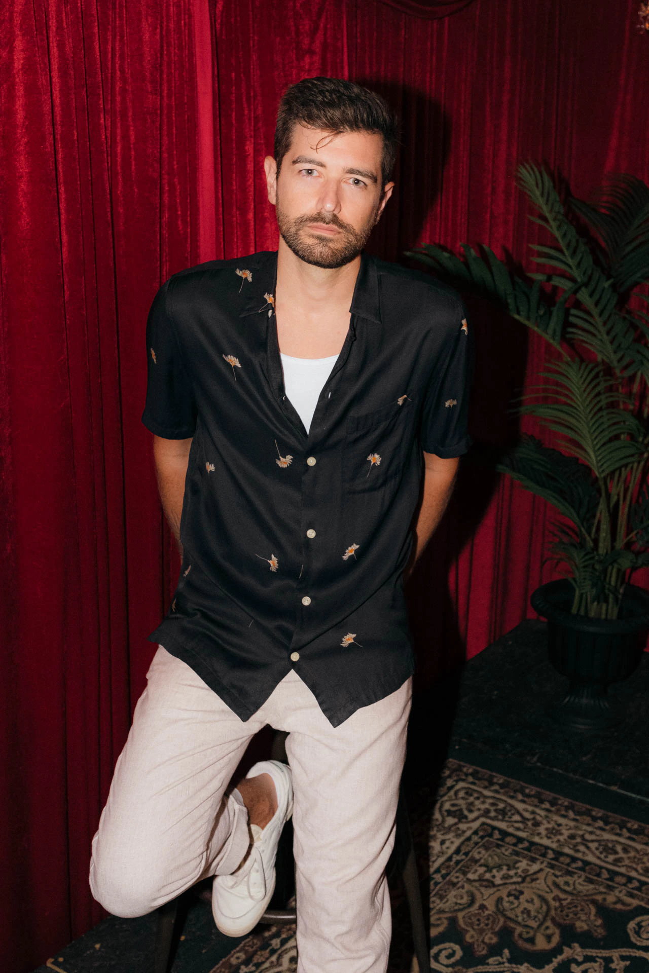 Portrait of Jonathan Grado in a daffodil shirt using heightened look flash photography. Red velvet background.
