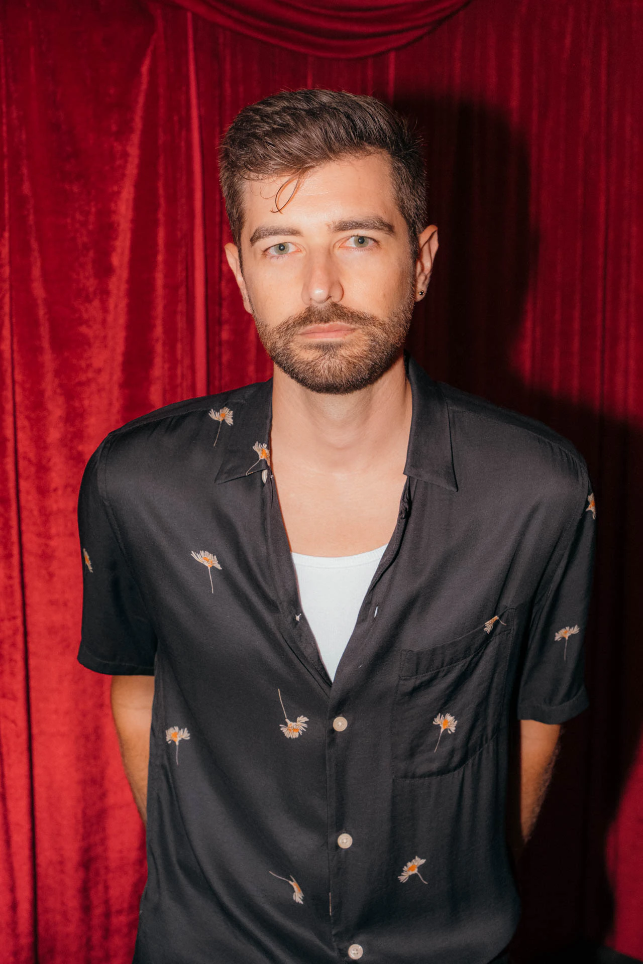 Portrait of Jonathan Grado in a daffodil shirt using heightened look flash photography. Red velvet background.