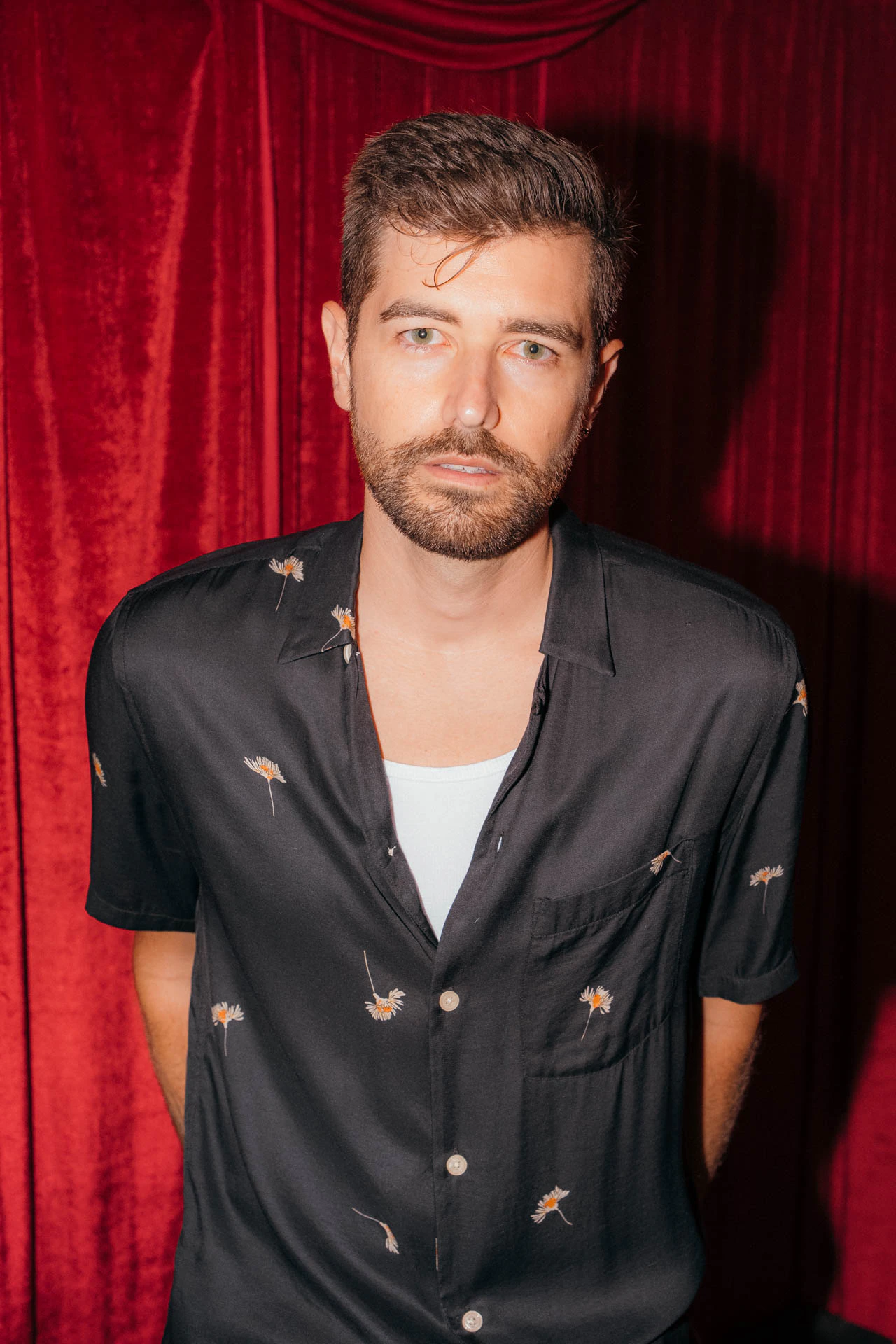Portrait of Jonathan Grado in a daffodil shirt using heightened look flash photography. Red velvet background.