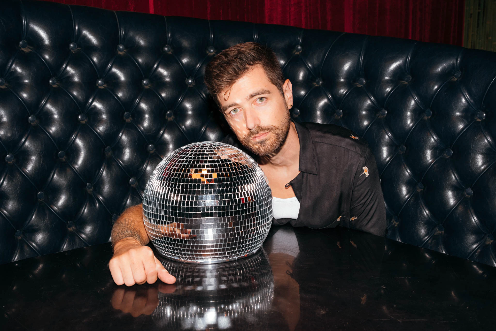 Portrait of Jonathan Grado in a daffodil shirt using heightened look flash photography. Resting on a disco ball.