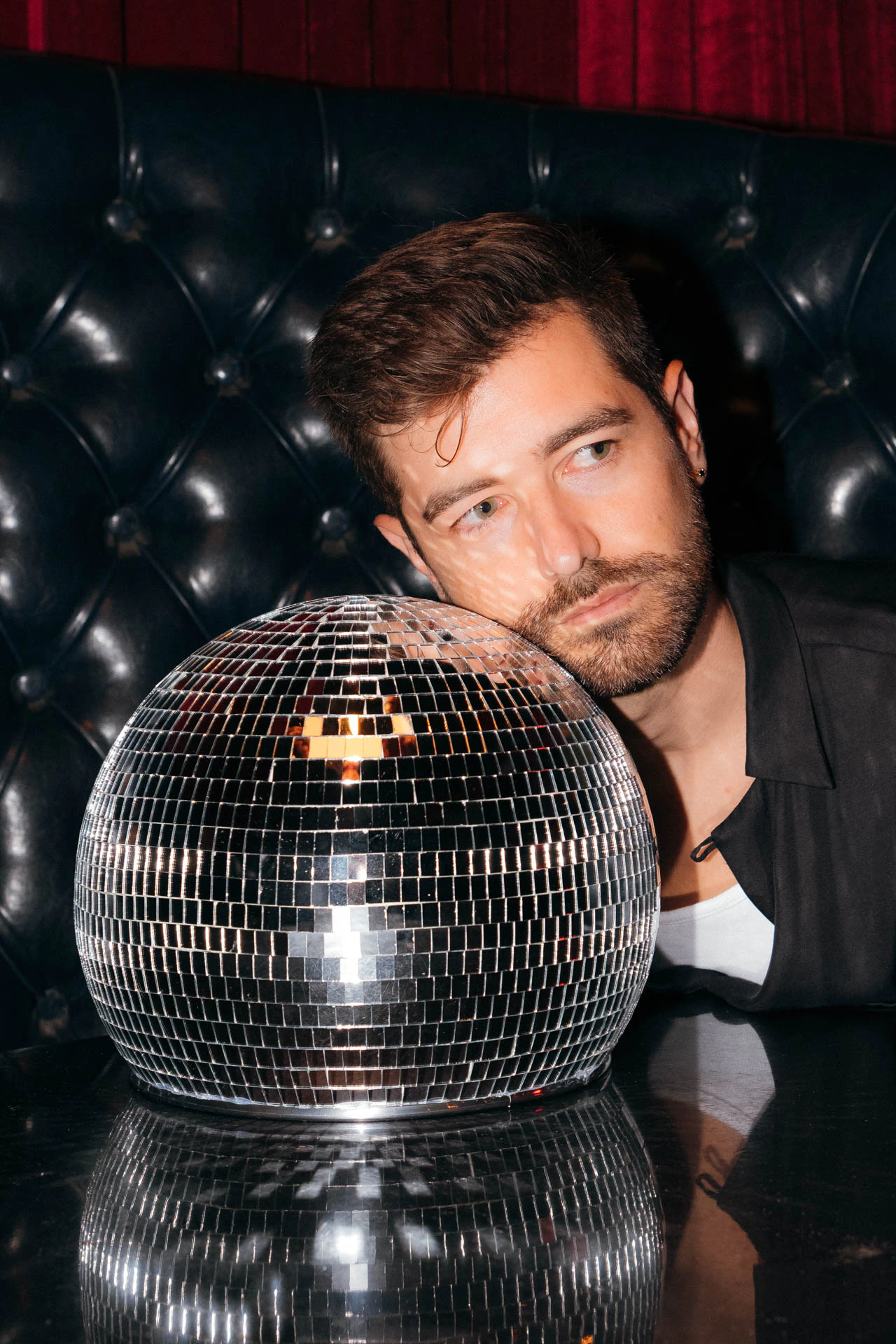 Portrait of Jonathan Grado in a daffodil shirt using heightened look flash photography. Resting on a disco ball.