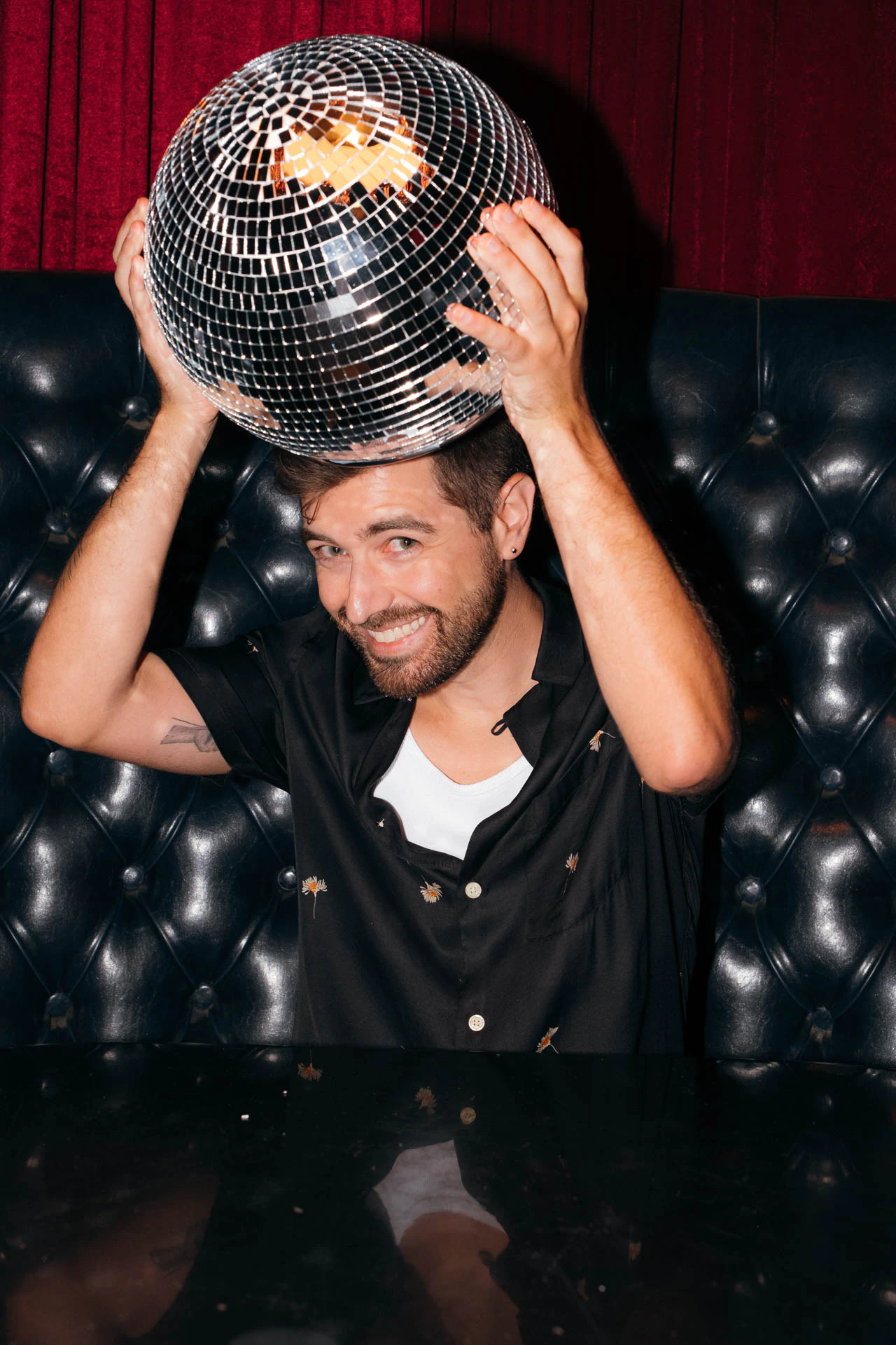 Portrait of Jonathan Grado in a daffodil shirt using heightened look flash photography. Resting on a disco ball.
