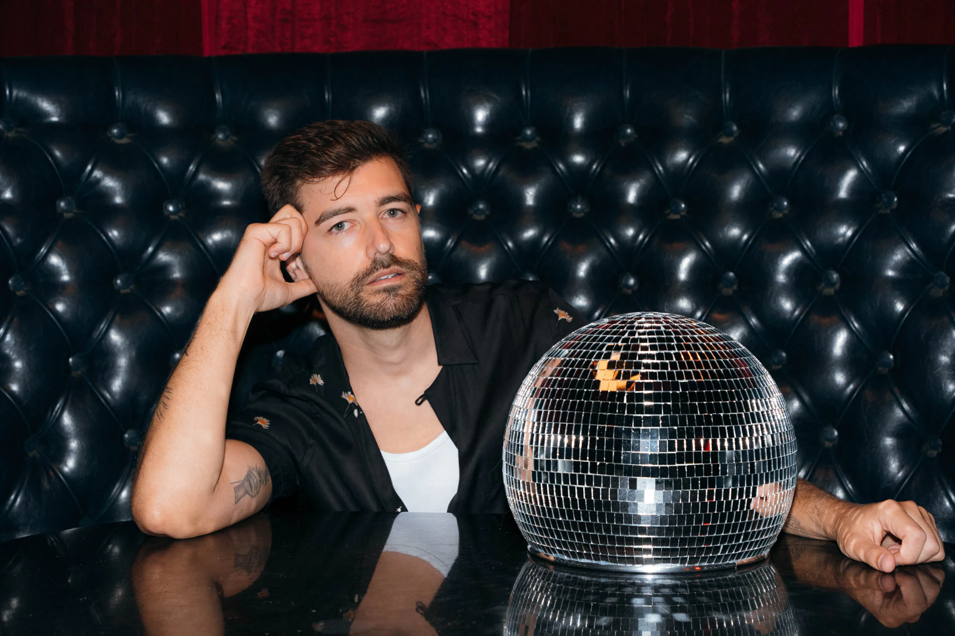 Portrait of Jonathan Grado in a daffodil shirt using heightened look flash photography. Resting on a disco ball.