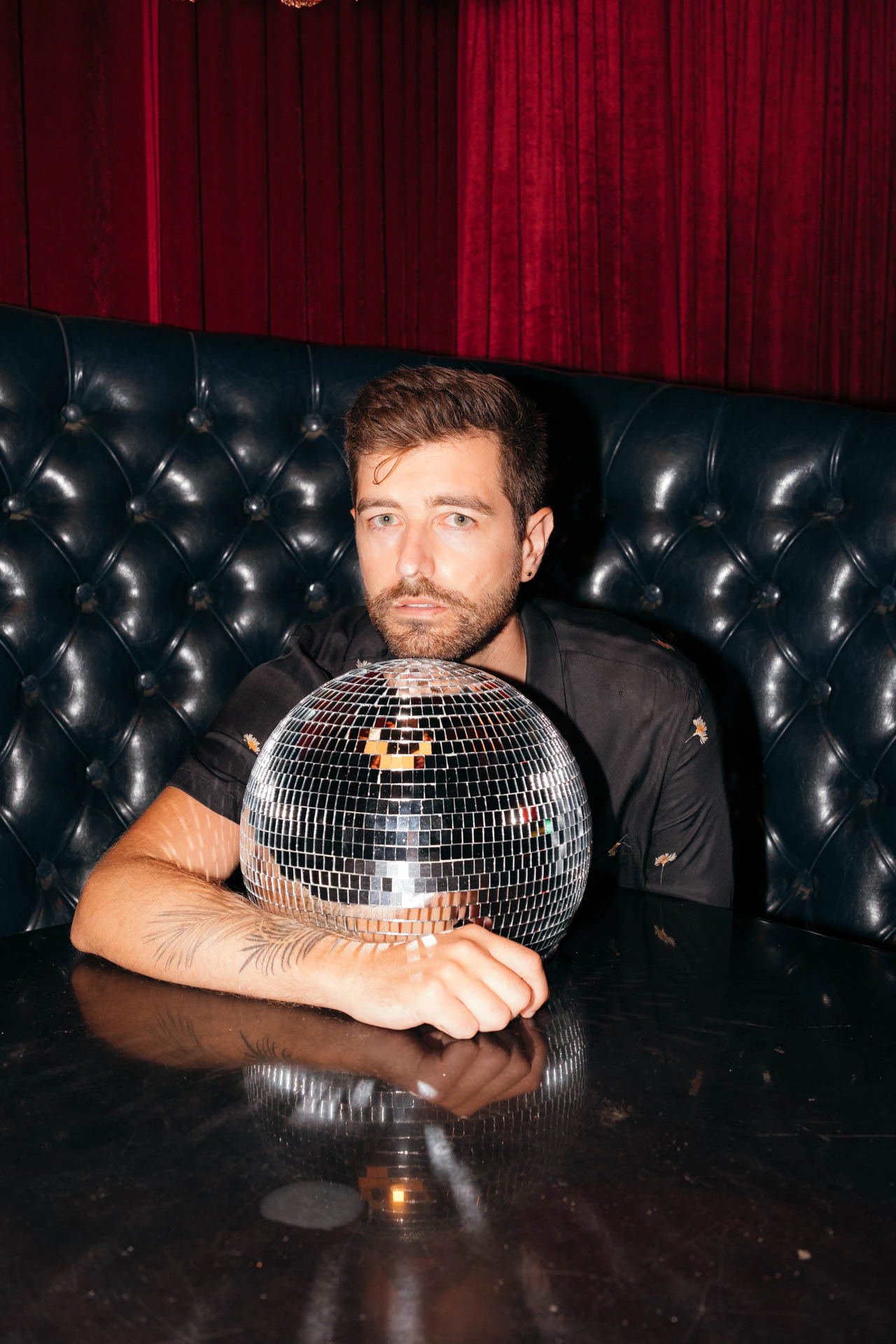 Portrait of Jonathan Grado in a daffodil shirt using heightened look flash photography. Resting on a disco ball.