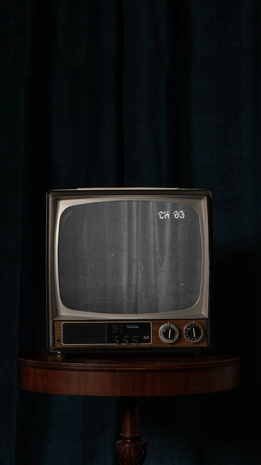 Old CRT TV with static in front of blue velvet.