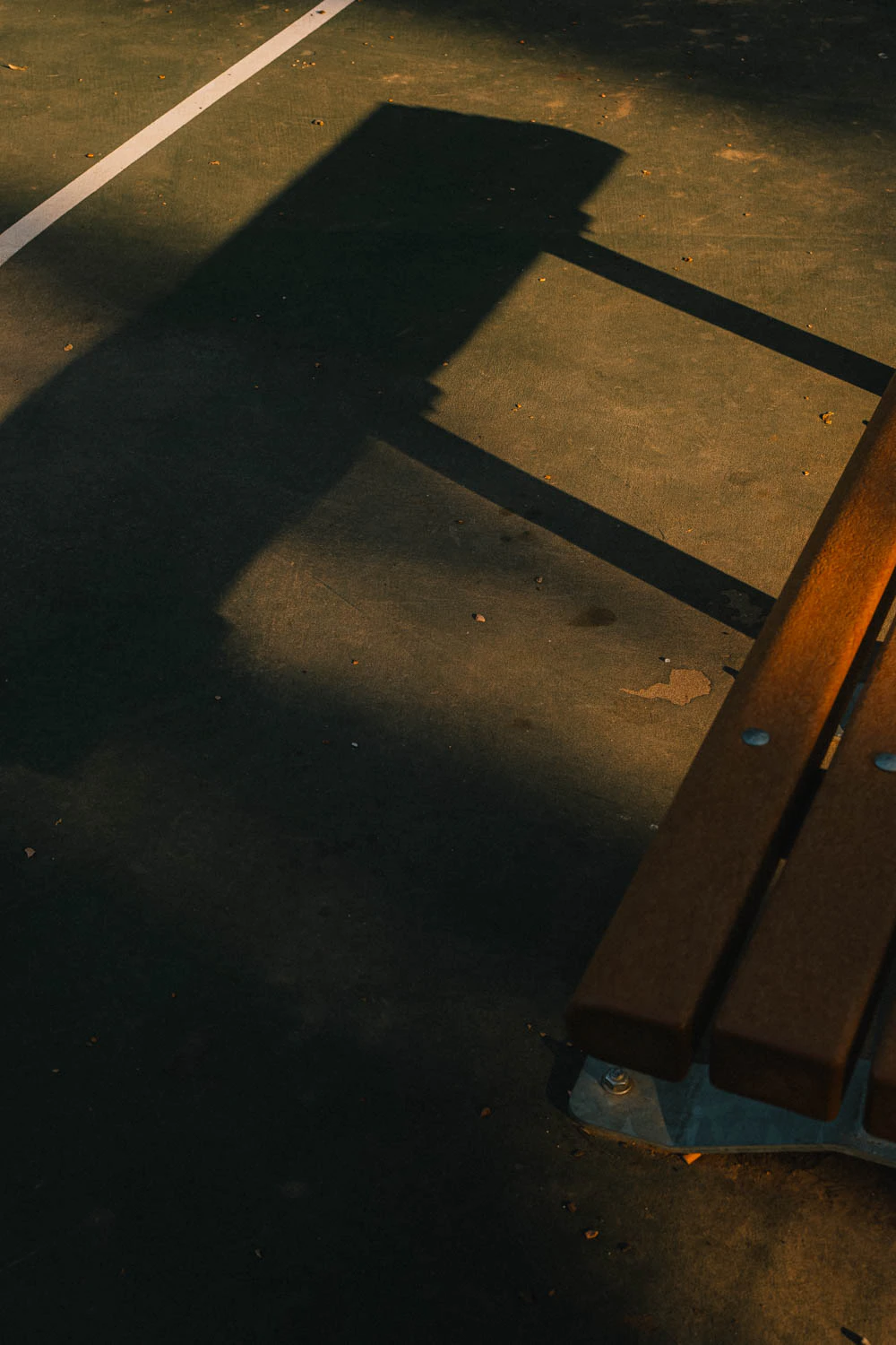 bench at abstract green and red basketball court lines at sunset