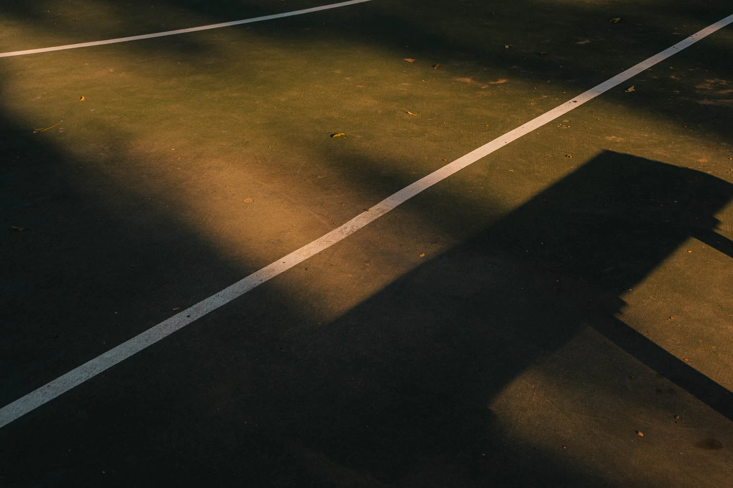 bench shadow at abstract green and red basketball court lines at sunset