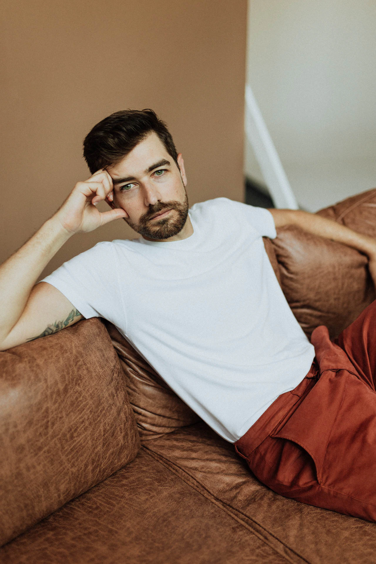 portrait of Jonathan Grado sitting down on a couch in red pants