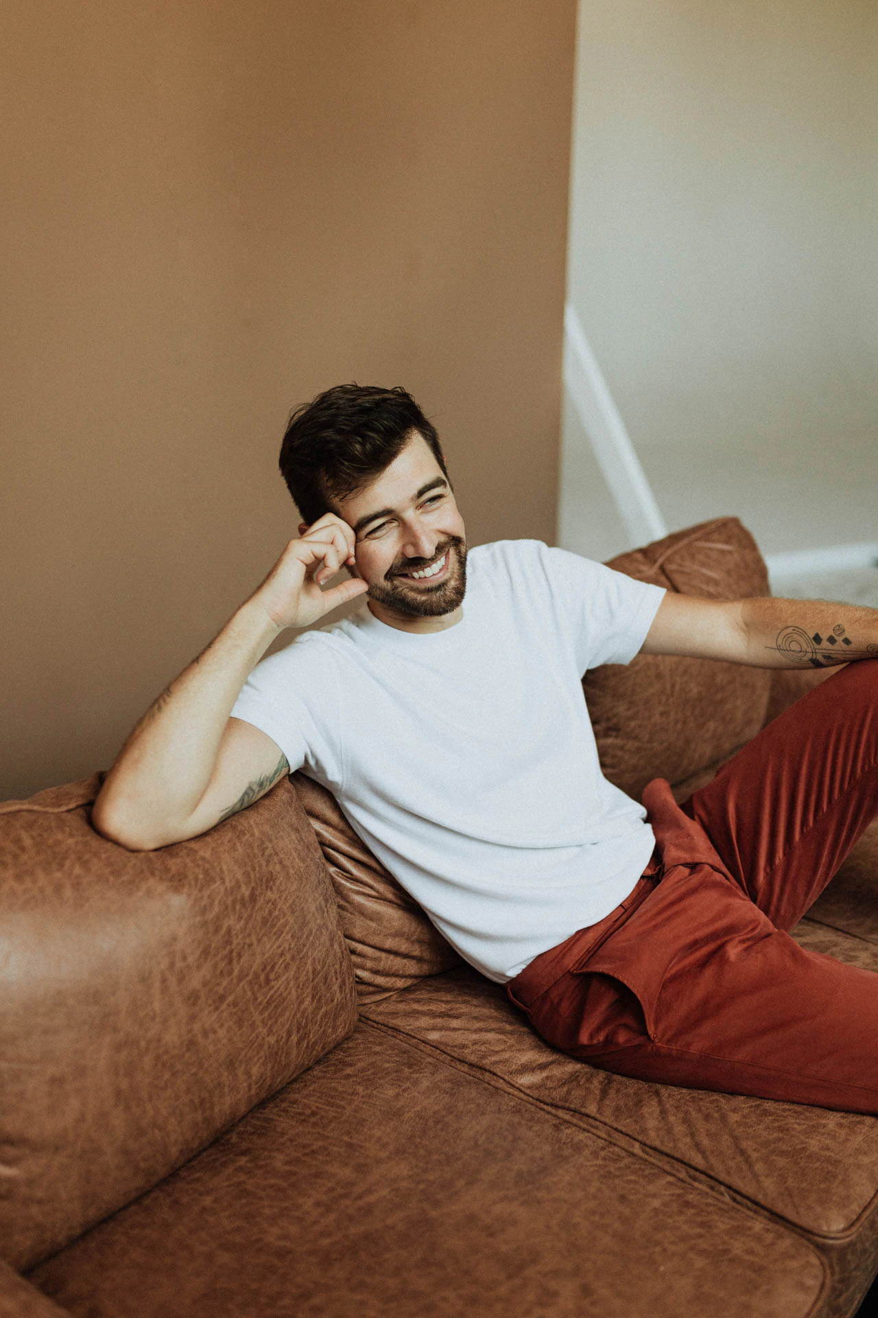 Jonathan Grado sitting  on a couch in red pants and smiling