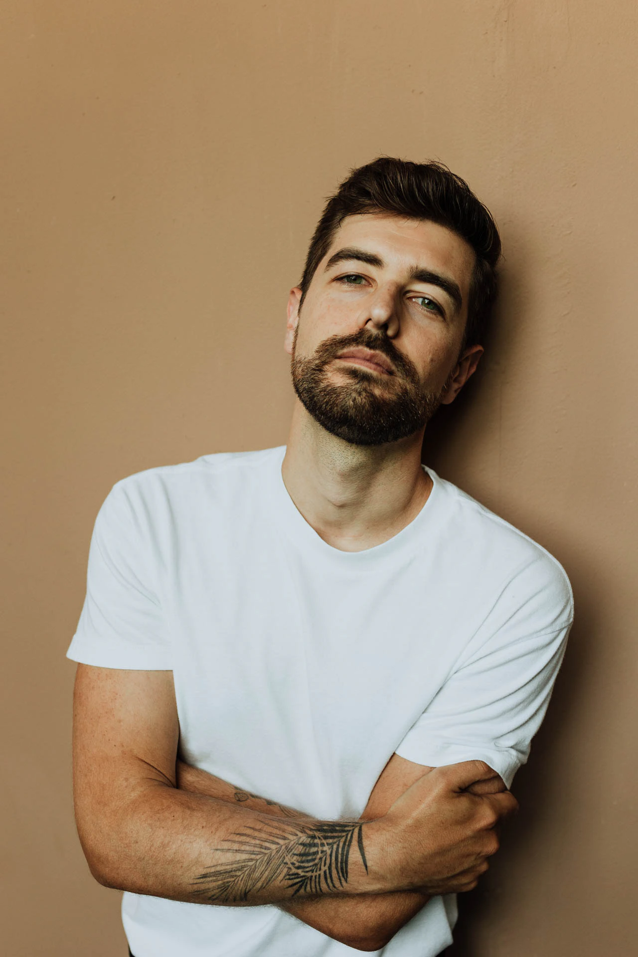 Jonathan Grado leaning on a wall in a white shirt