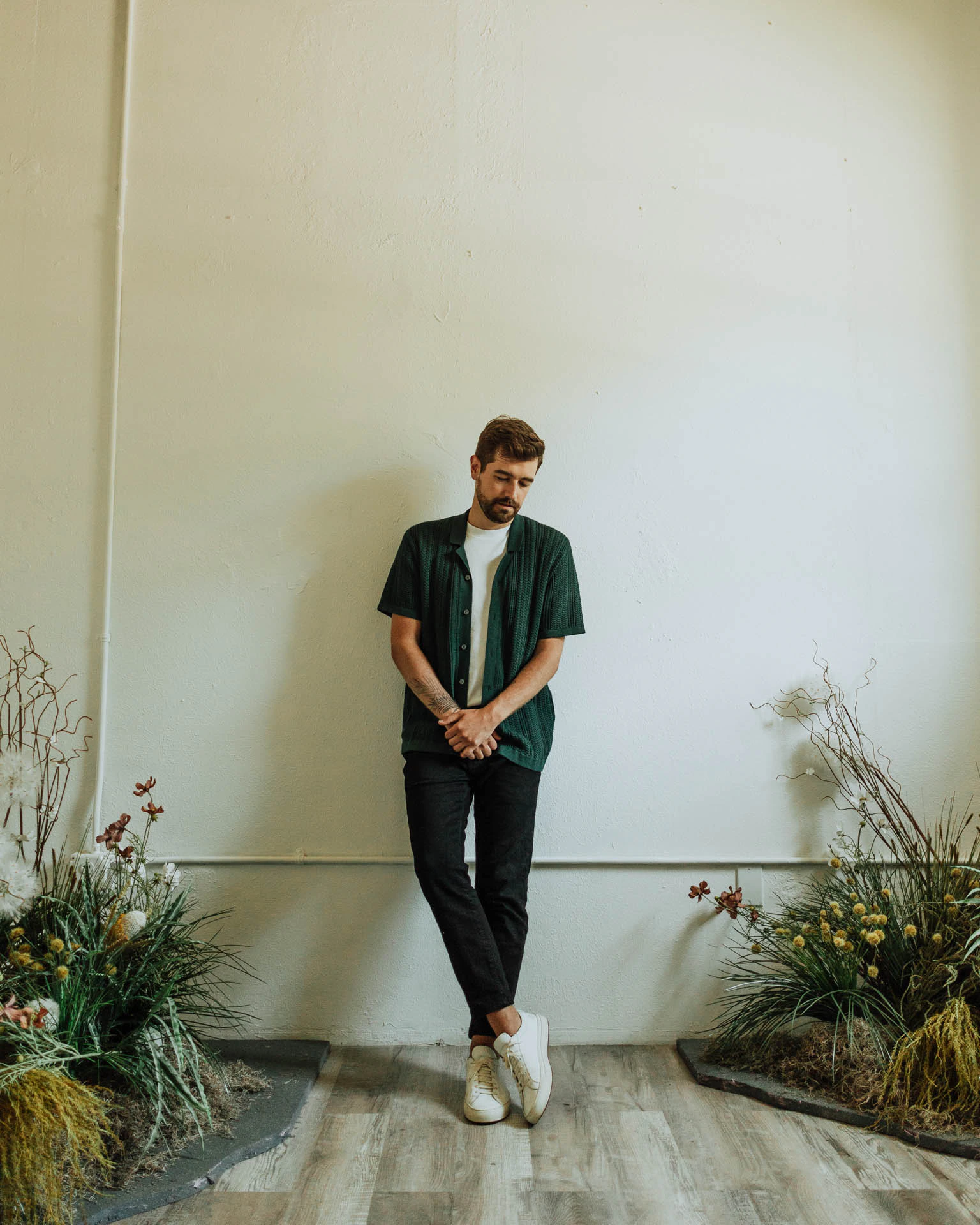 Jonathan Grado leaning on a wall near flowers