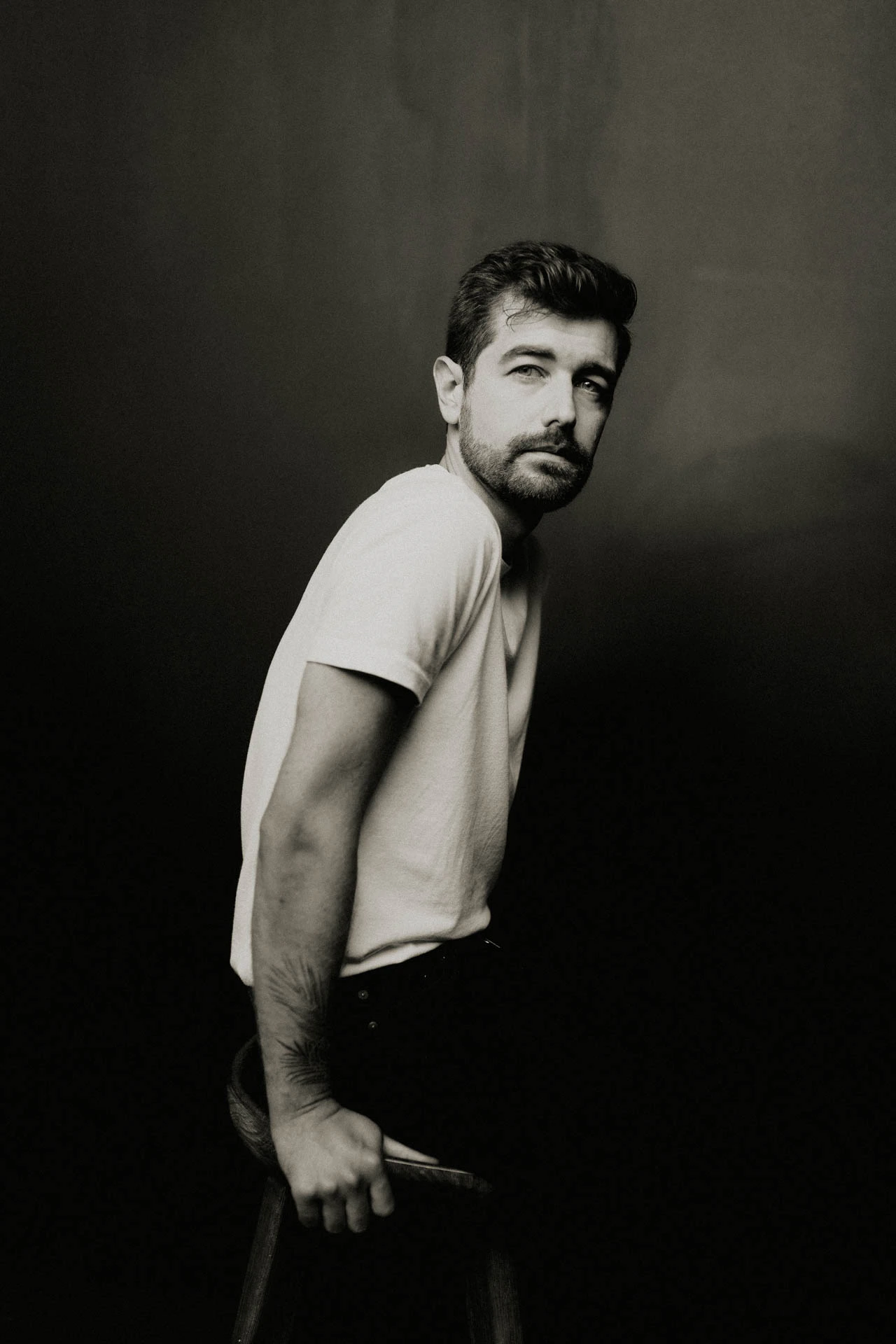 Jonathan Grado on a stool in black and white