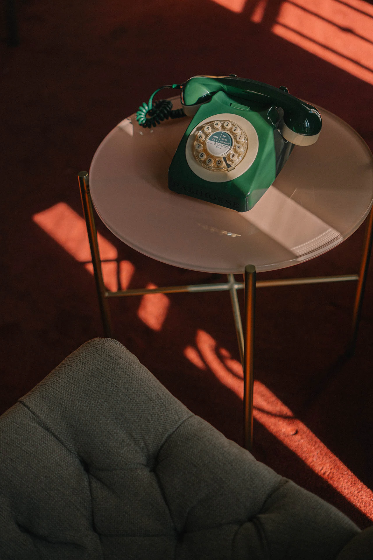An old green rotary phone with a blue briefcase. An old hotel with red carpet. Sunset.