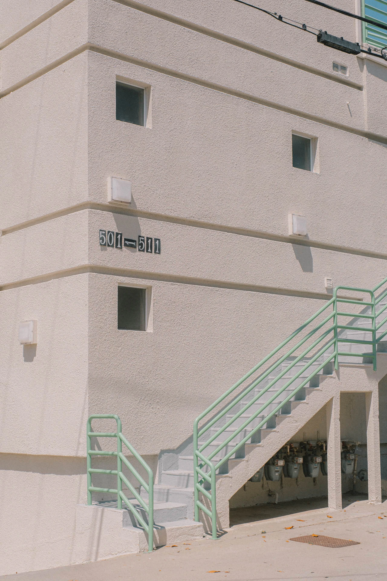 green banister on stairs of cream building in Santa Monica