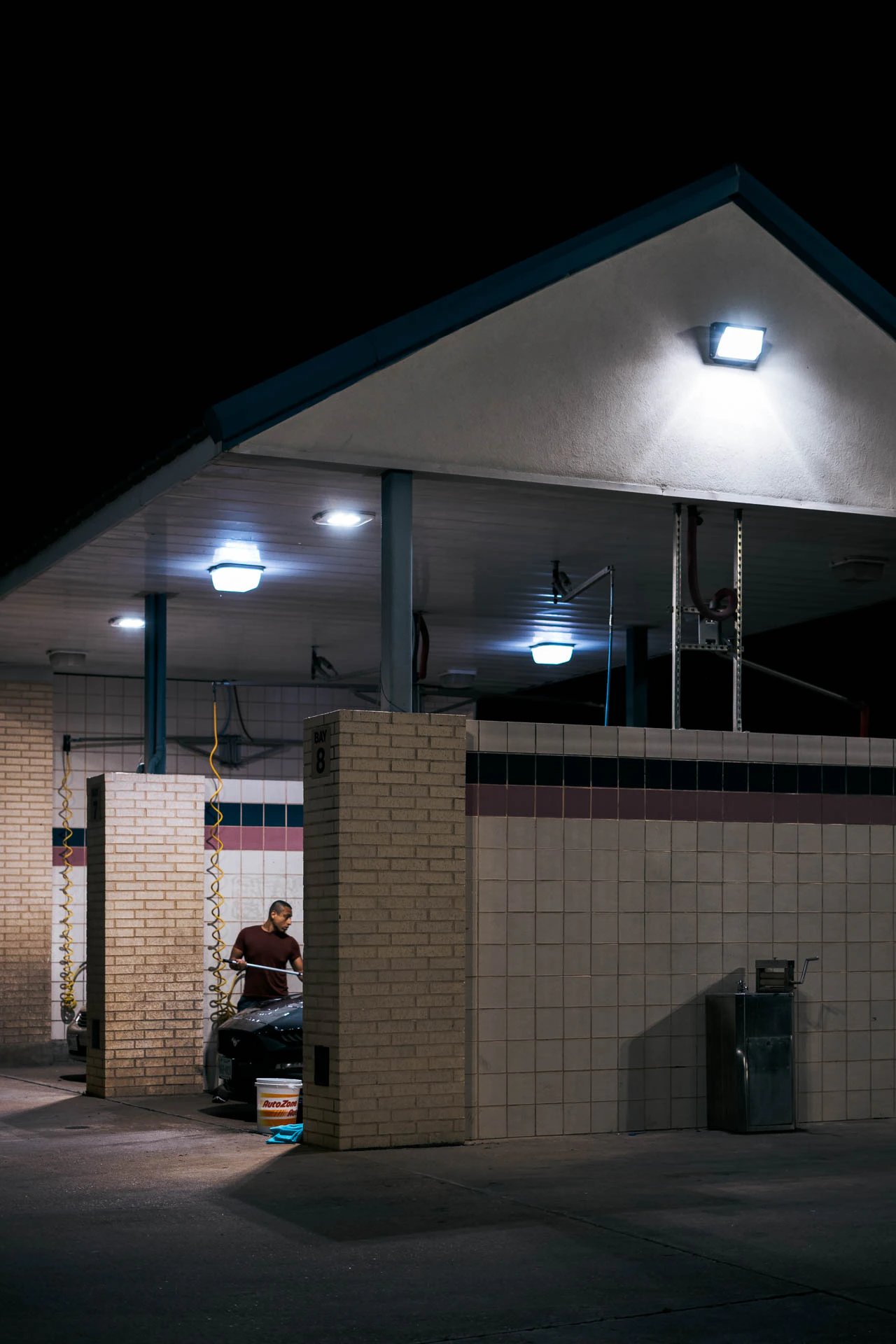 man washing his car at night
