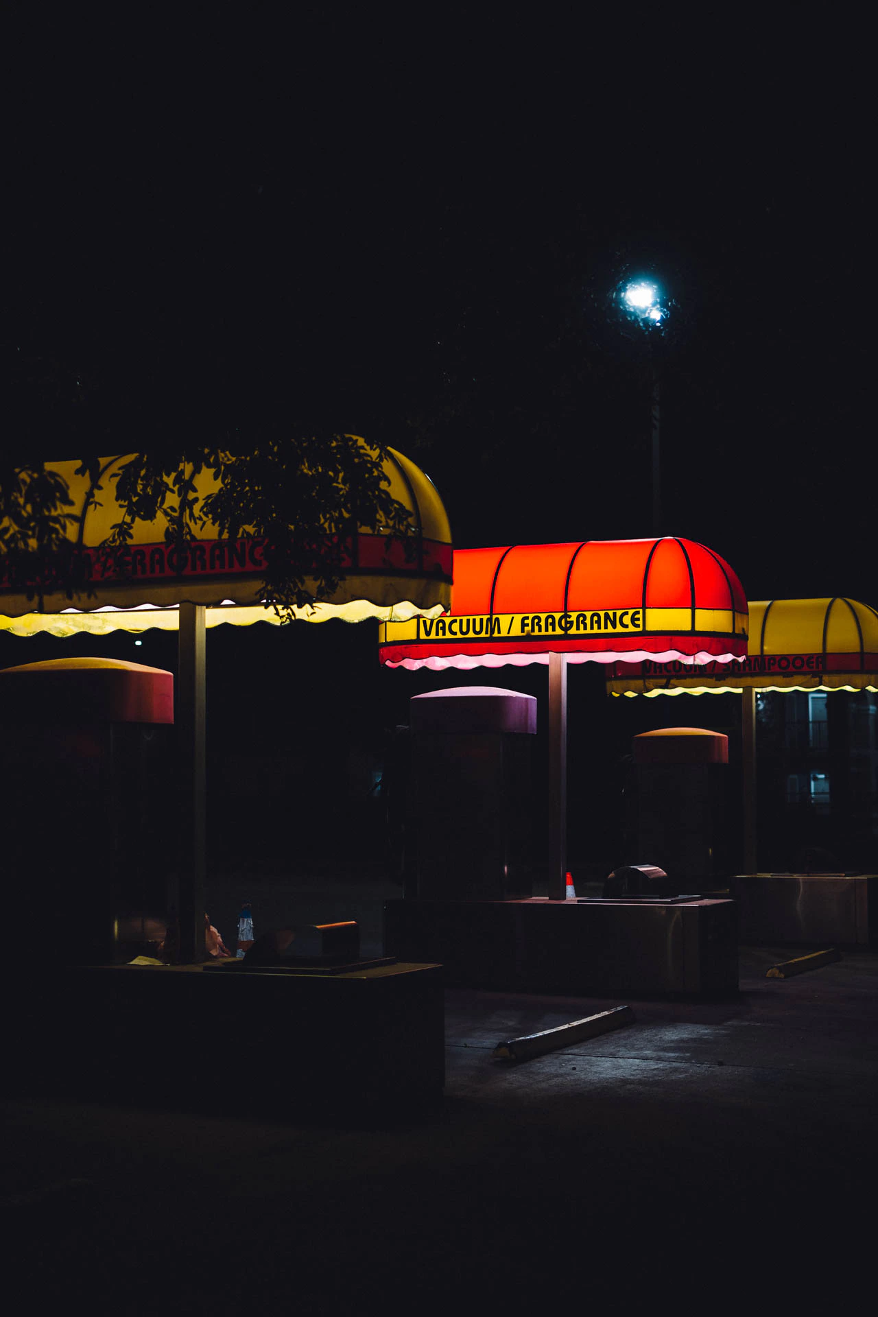 retro car wash with yellow and red awnings reading vacuum fragrance at night