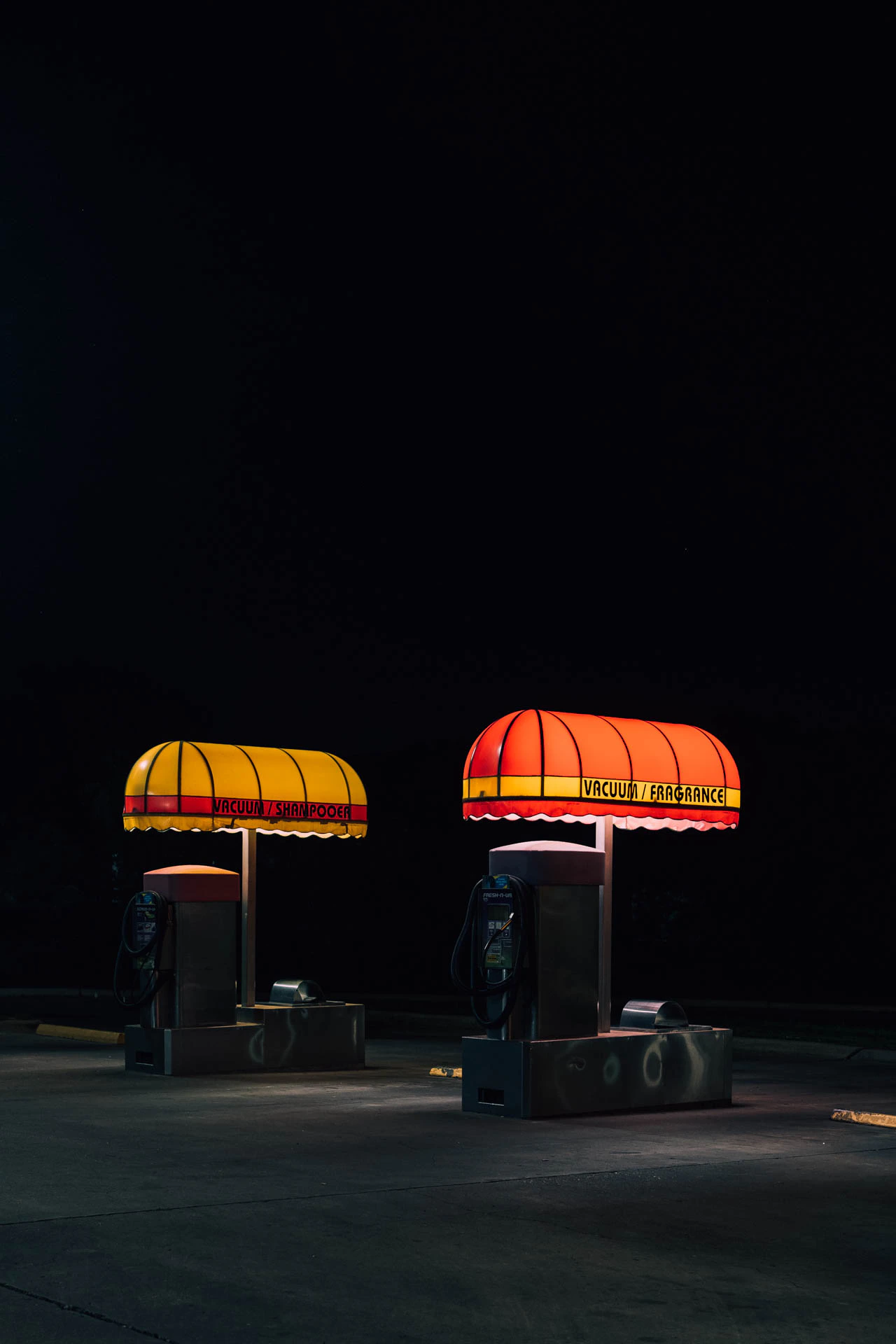 retro car wash with yellow and red awnings reading vacuum fragrance at night