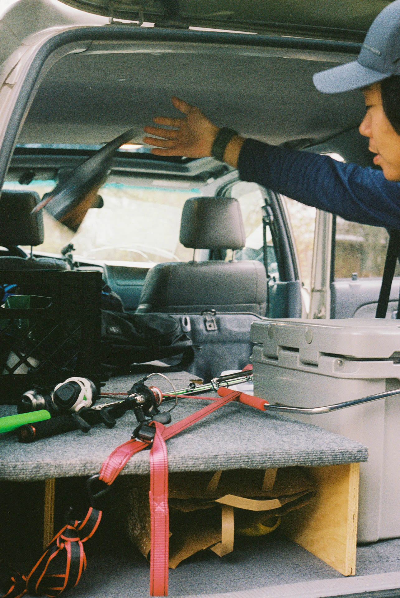 man throwing fishing equipment into a jeep